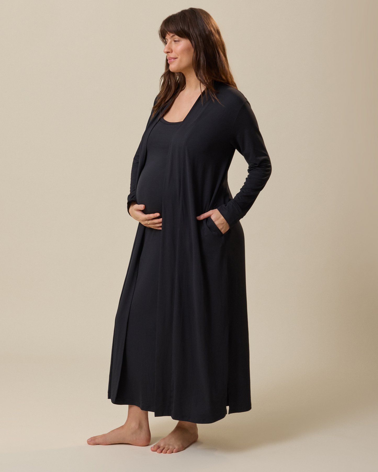 Woman wearing a black long-sleeve duster against a beige background@model_info:KJ is 5'9" and wearing a Medium.