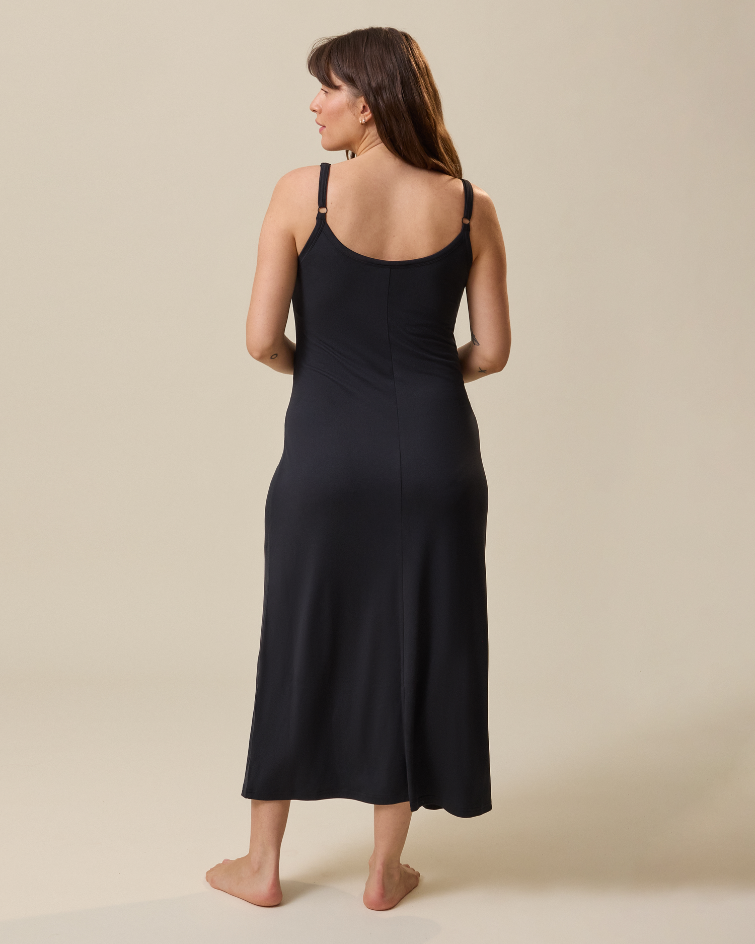 Woman wearing a black lounge dress against a beige background