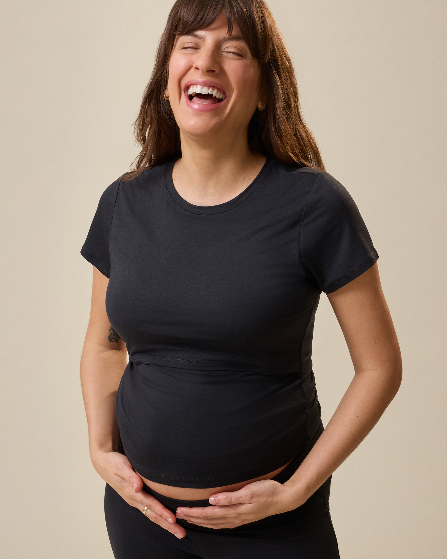 Woman wearing a black t-shirt against a beige background
