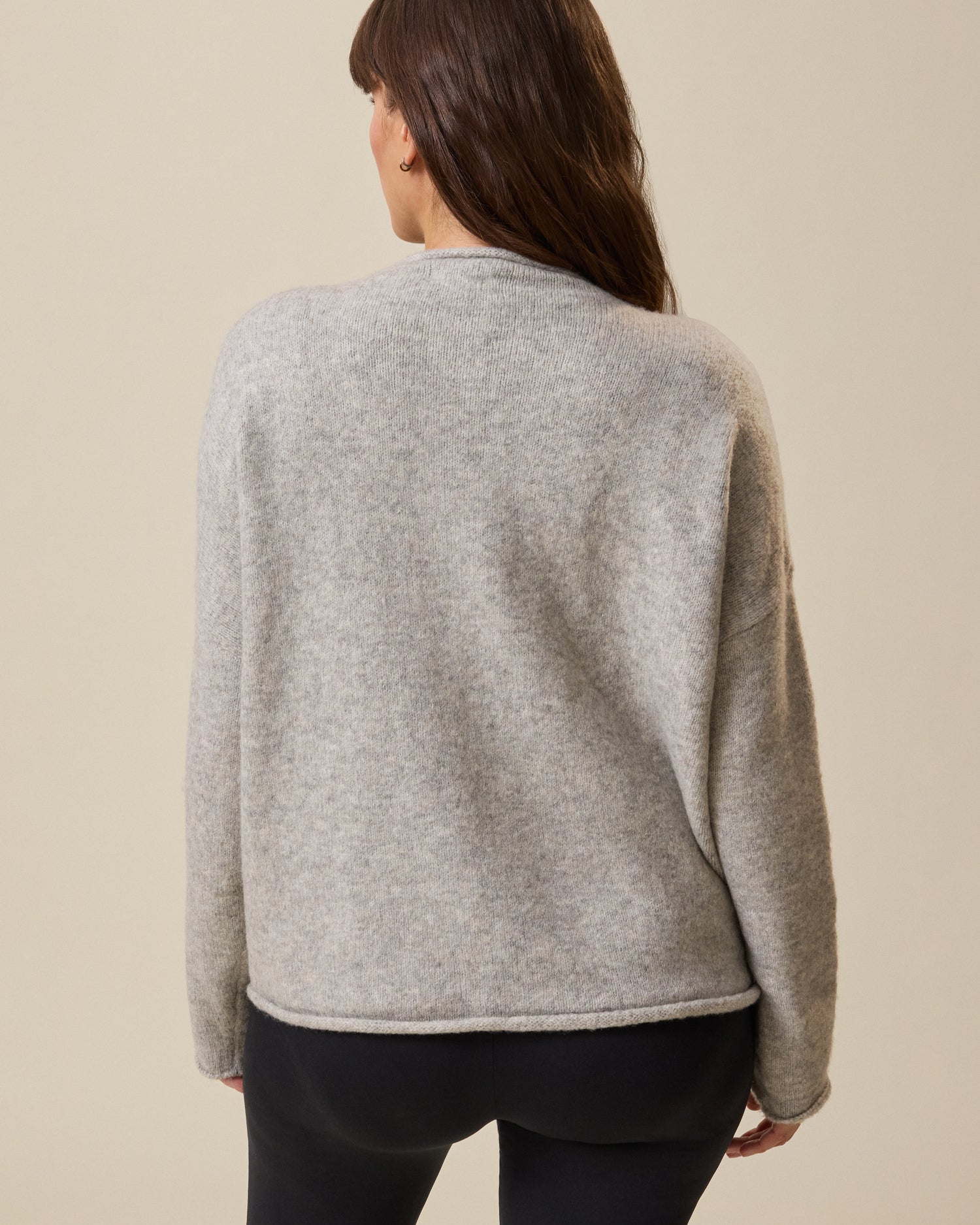 Person wearing a gray sweater on a beige background