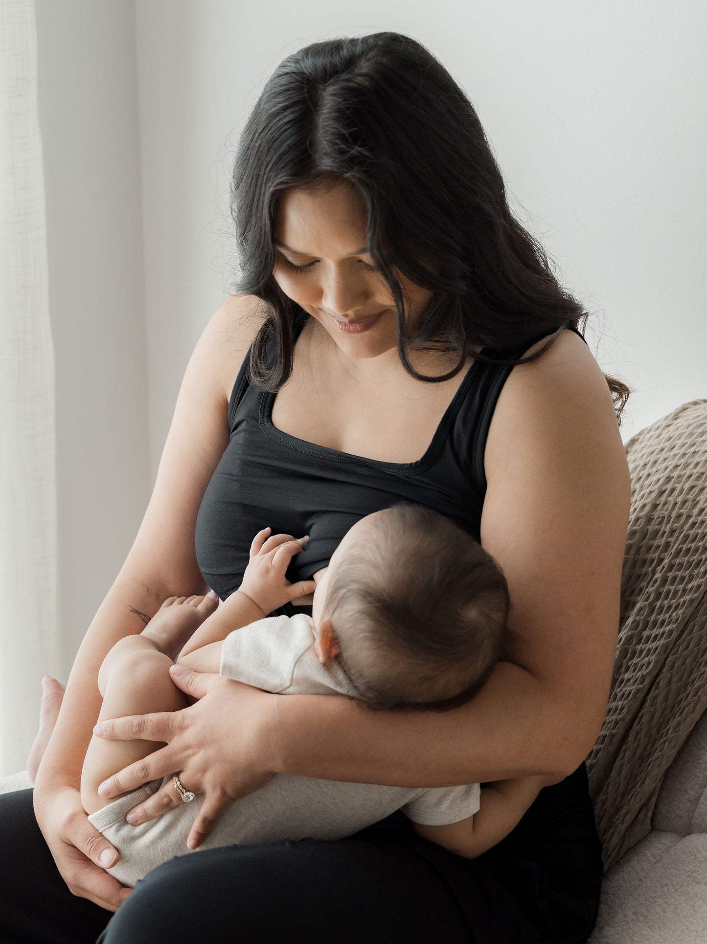 Model breastfeeding her baby while wearing the Everyday Essential Nursing Tank in Black.