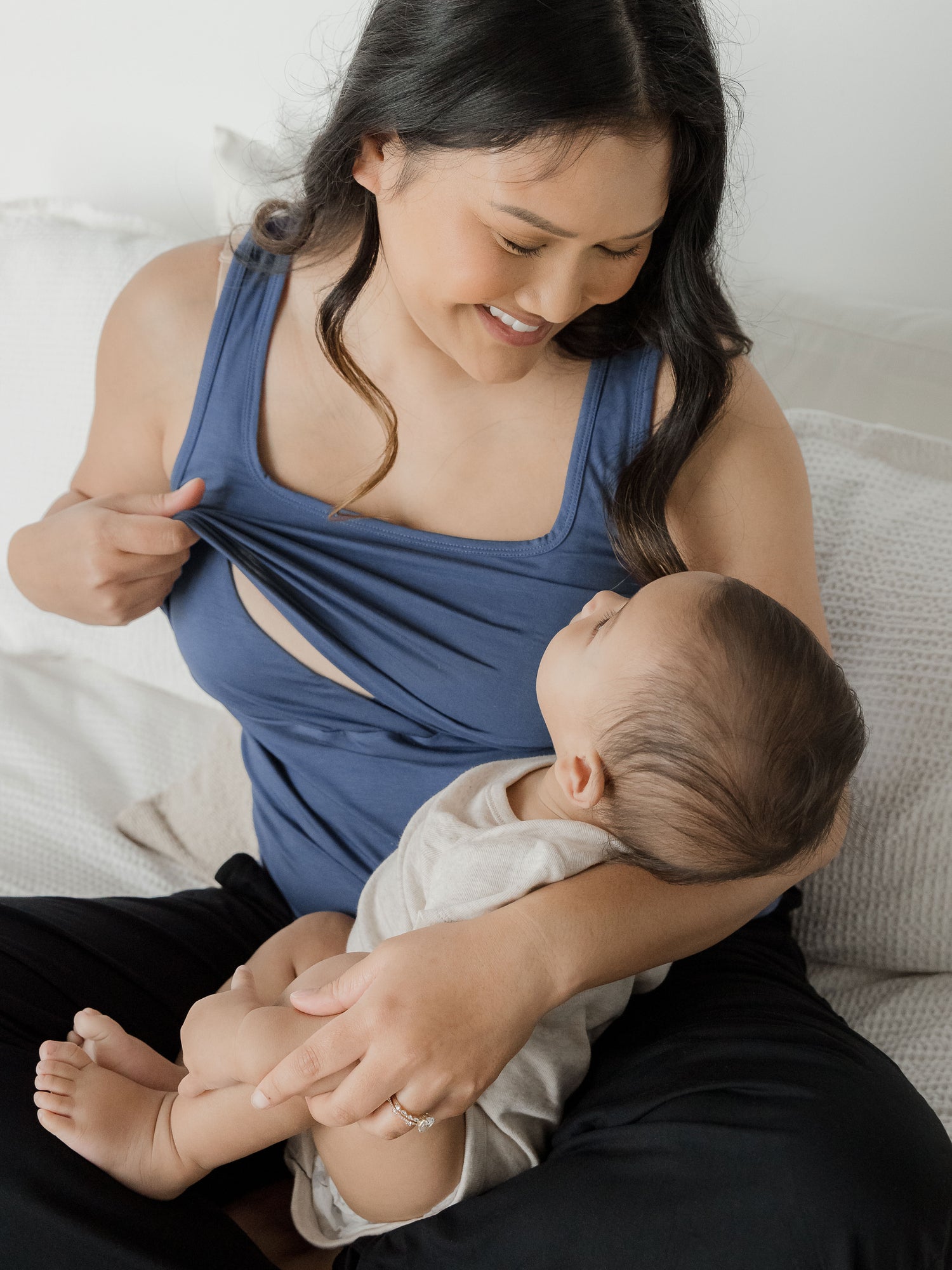 Model holding her baby in her lap while wearing the Everyday Essential Nursing Tank in Slate Blue showing the easy pull up nursing access.