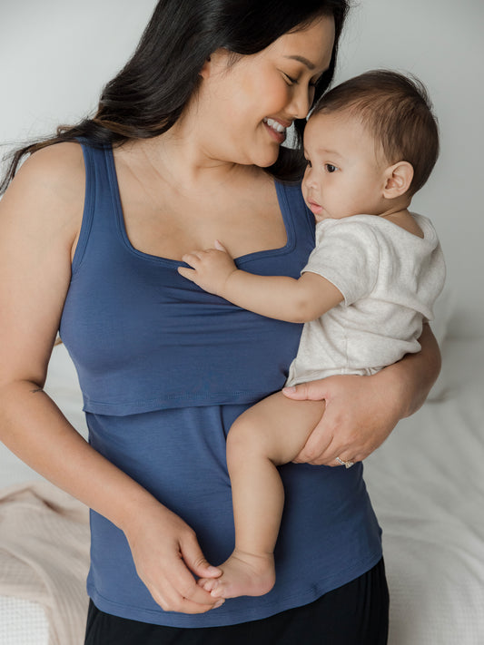Model holding her baby while wearing the Everyday Essential Nursing Tank in Slate Blue. @model_info:Binc is wearing a Medium.