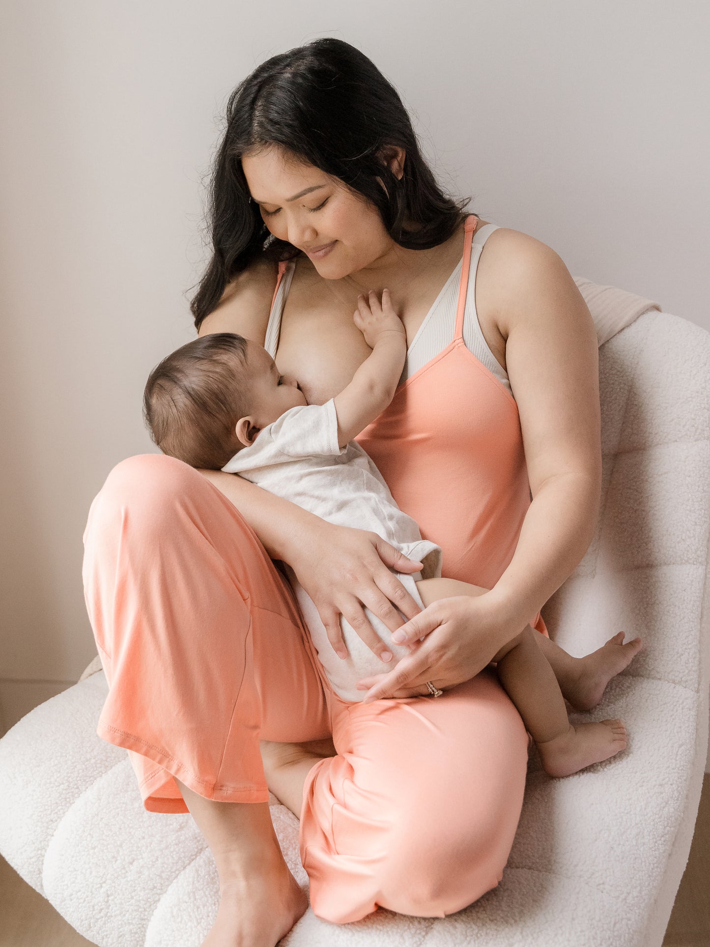 Model breastfeeding her baby while wearing the Charlie Maternity & Nursing Romper in Vintage Coral.