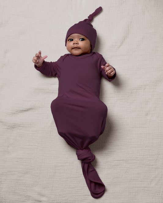 Bamboo Knotted Baby Gown in Burgundy Plum lying on a light gray blanket@model_info:Luna is 6 weeks old.