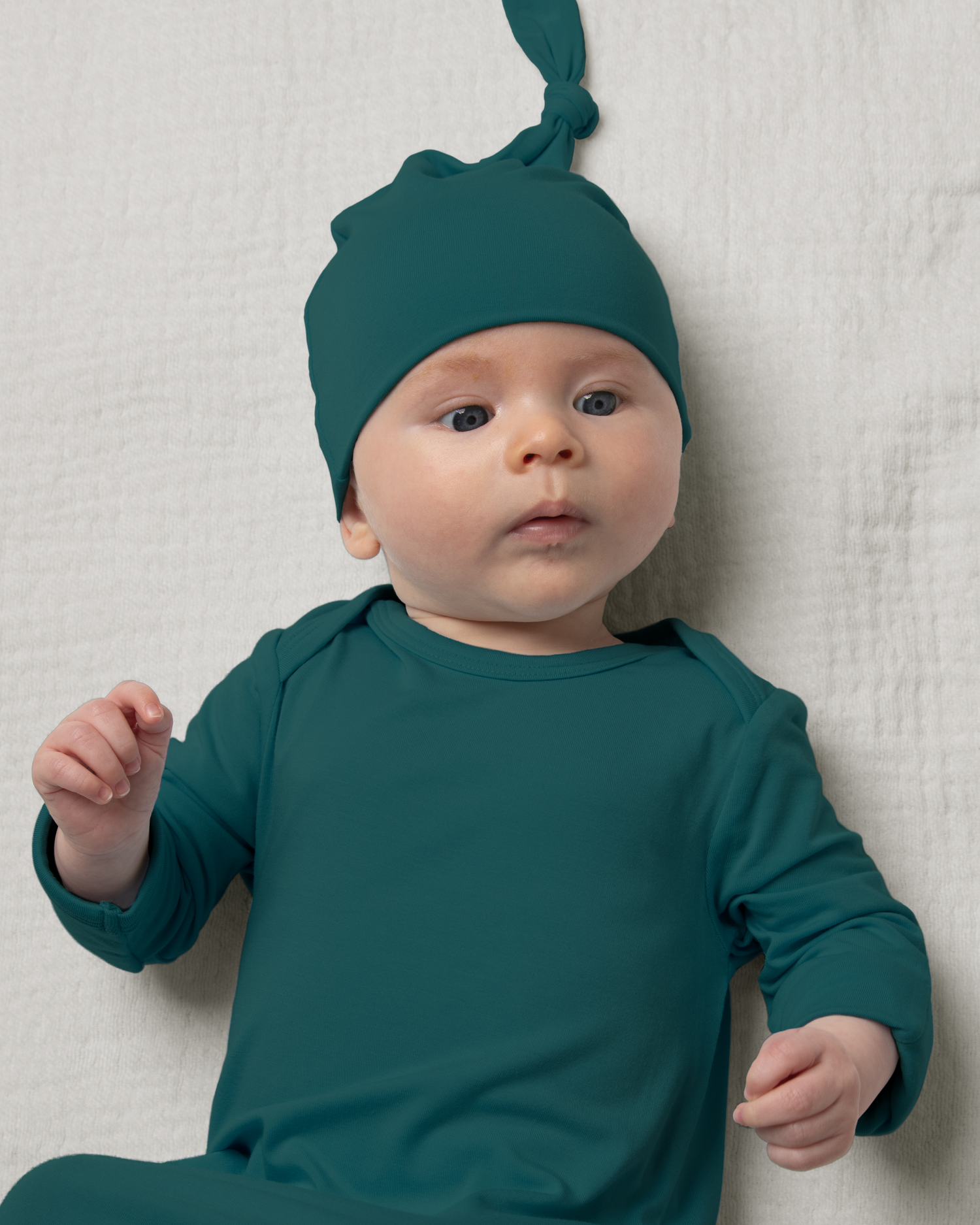 Baby wearing Bamboo Knotted Baby Gown in Evergreen against a light background