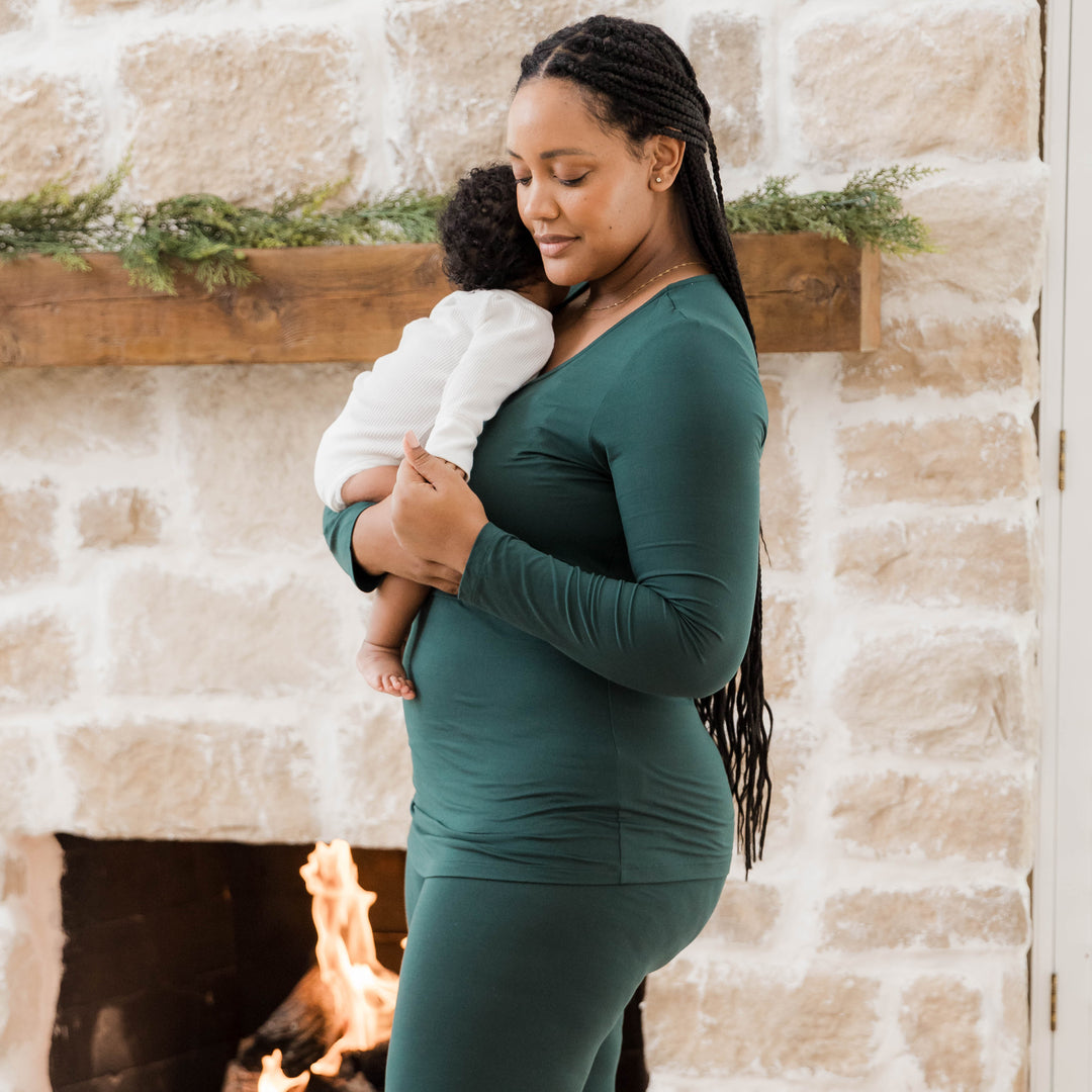 Model wearing the Jane Nursing Pajama Set in Evergreen while holding her baby.
