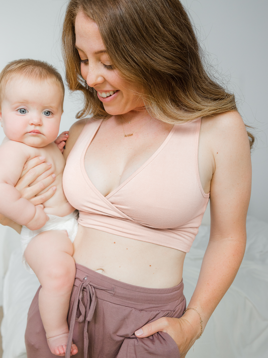 Model wearing the French Terry Racerback Nursing & Sleep Bra in in Soft Pink, holding baby@model_info:Ashley is wearing a Small.
