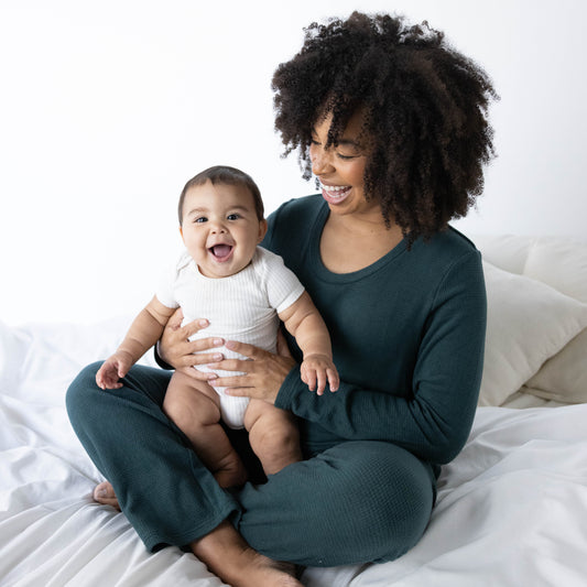 Model wearing the Fleece Nursing & Maternity Pajama Set in Evergreen with her baby in her lap. @model_info:Tess is wearing a Small.