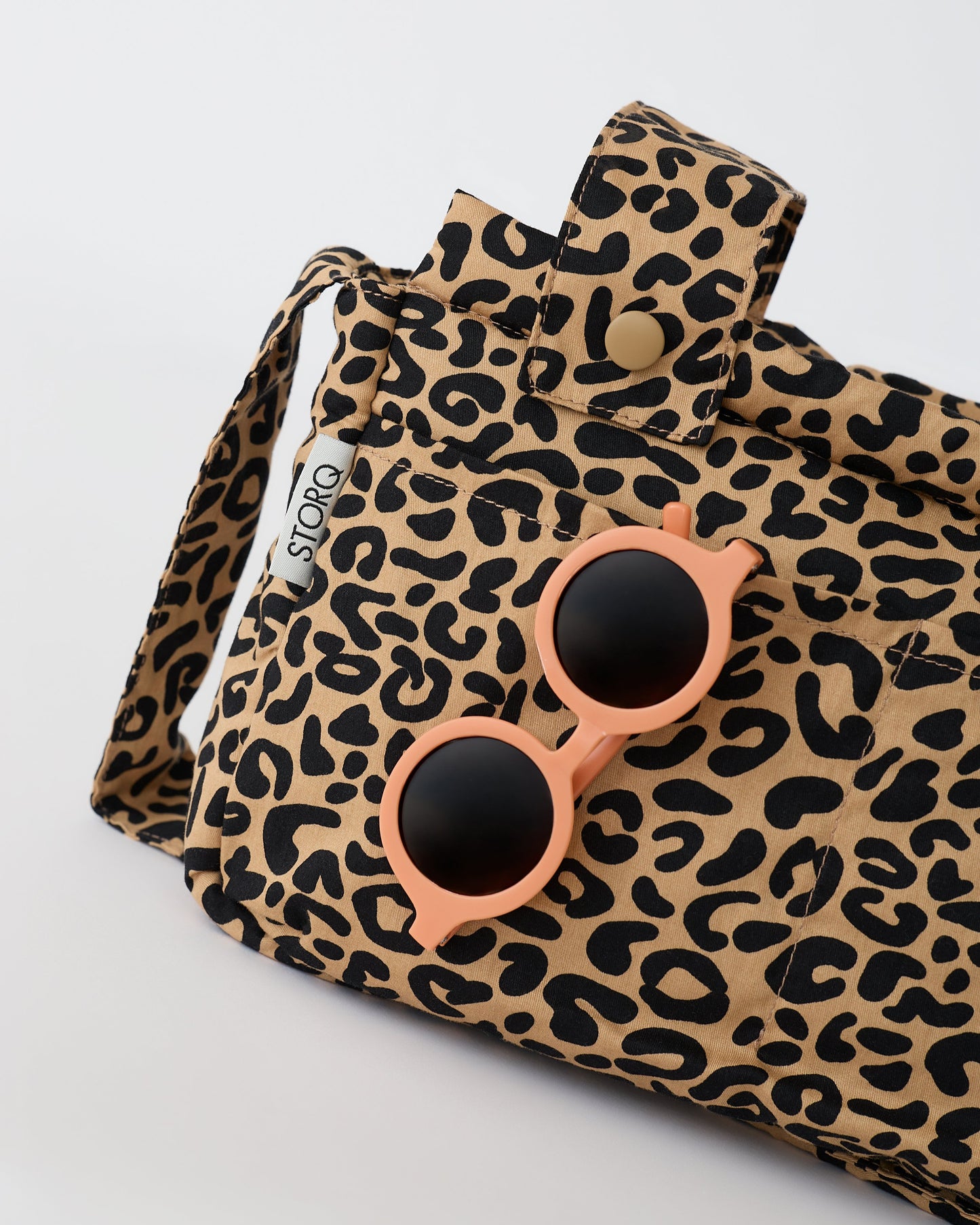 Close up of the pockets of the Stroller Party™ Caddy Bag in Leopard on a beige background.