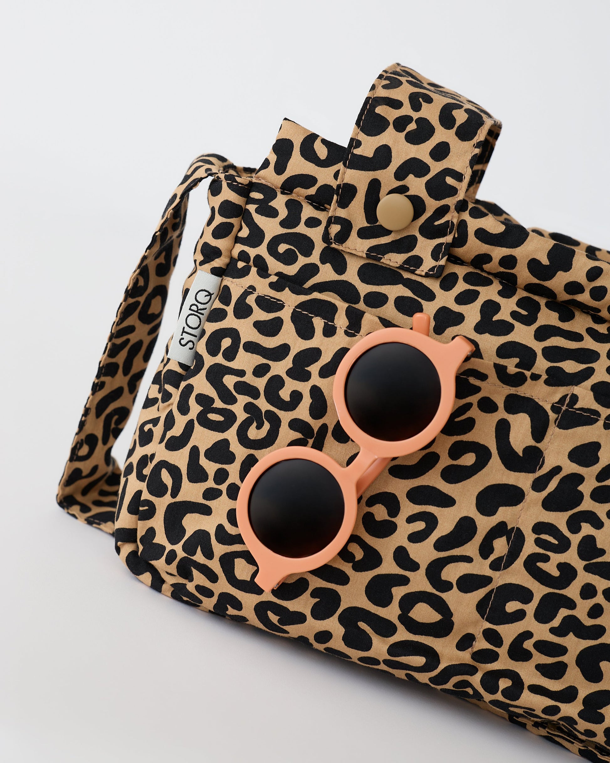 Close up of the pockets of the Stroller Party™ Caddy Bag in Leopard on a beige background.