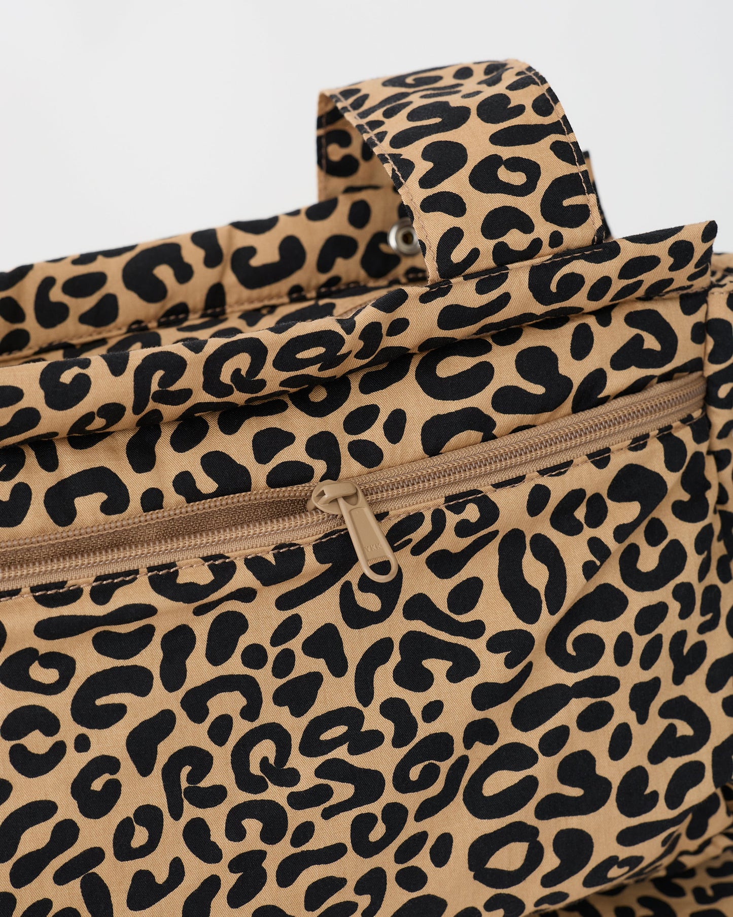 Close up of the zipper and strap of the Stroller Party™ Caddy Bag in Leopard on a beige background.