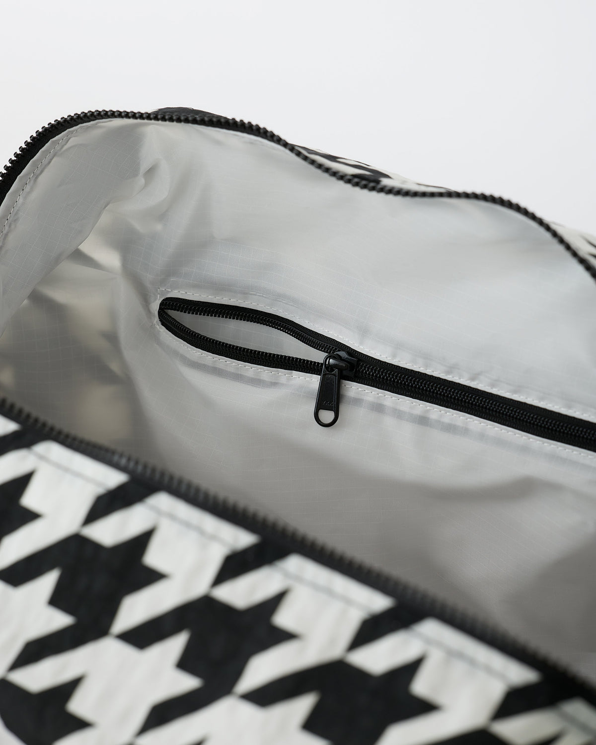 Close up of the interior of the Large Weekender Bag in Black Houndstooth on an off white background.