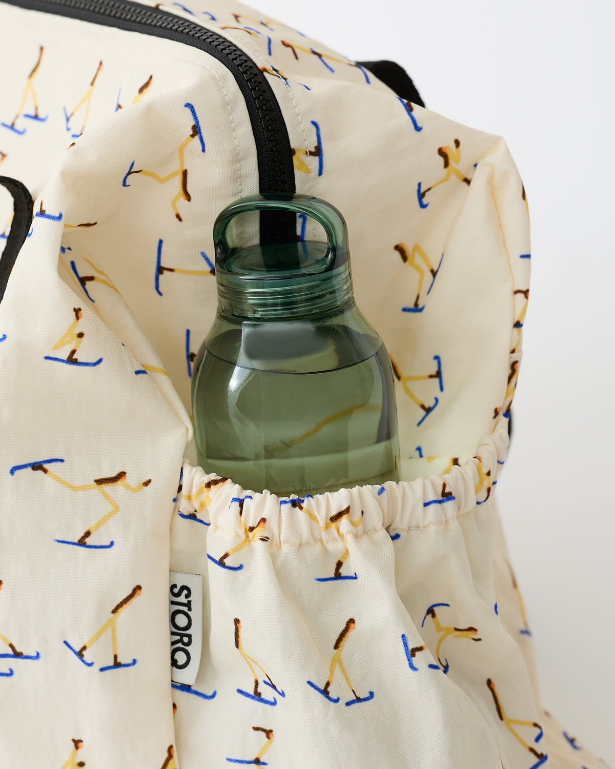 Close up on the side pocket holding a water bottle, on the Large Weekender Bag in Ivory Ski, on an off white background.