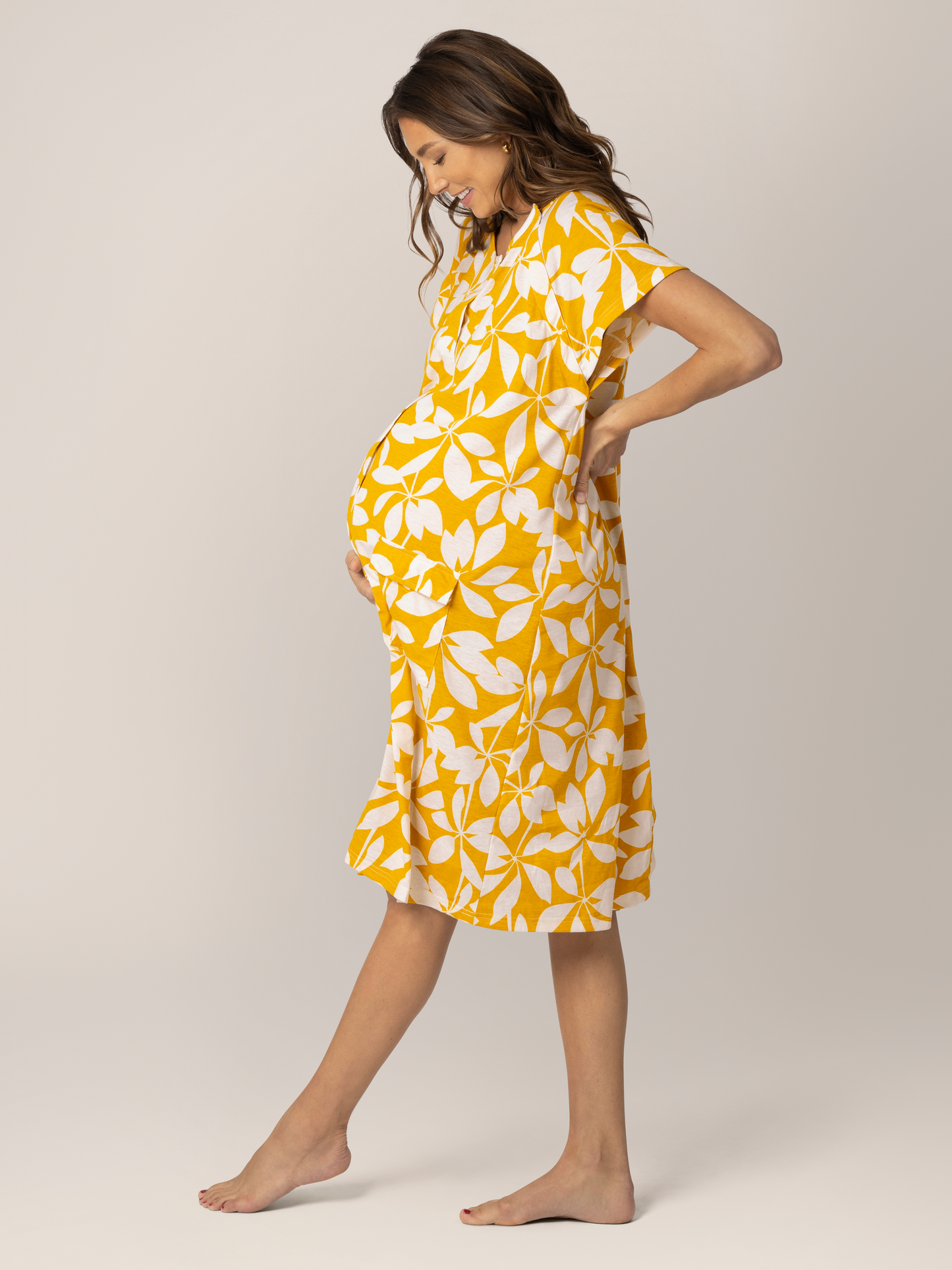 Profile view of pregnant model wearing the Universal Labor & Delivery Gown in Honey Leaf.