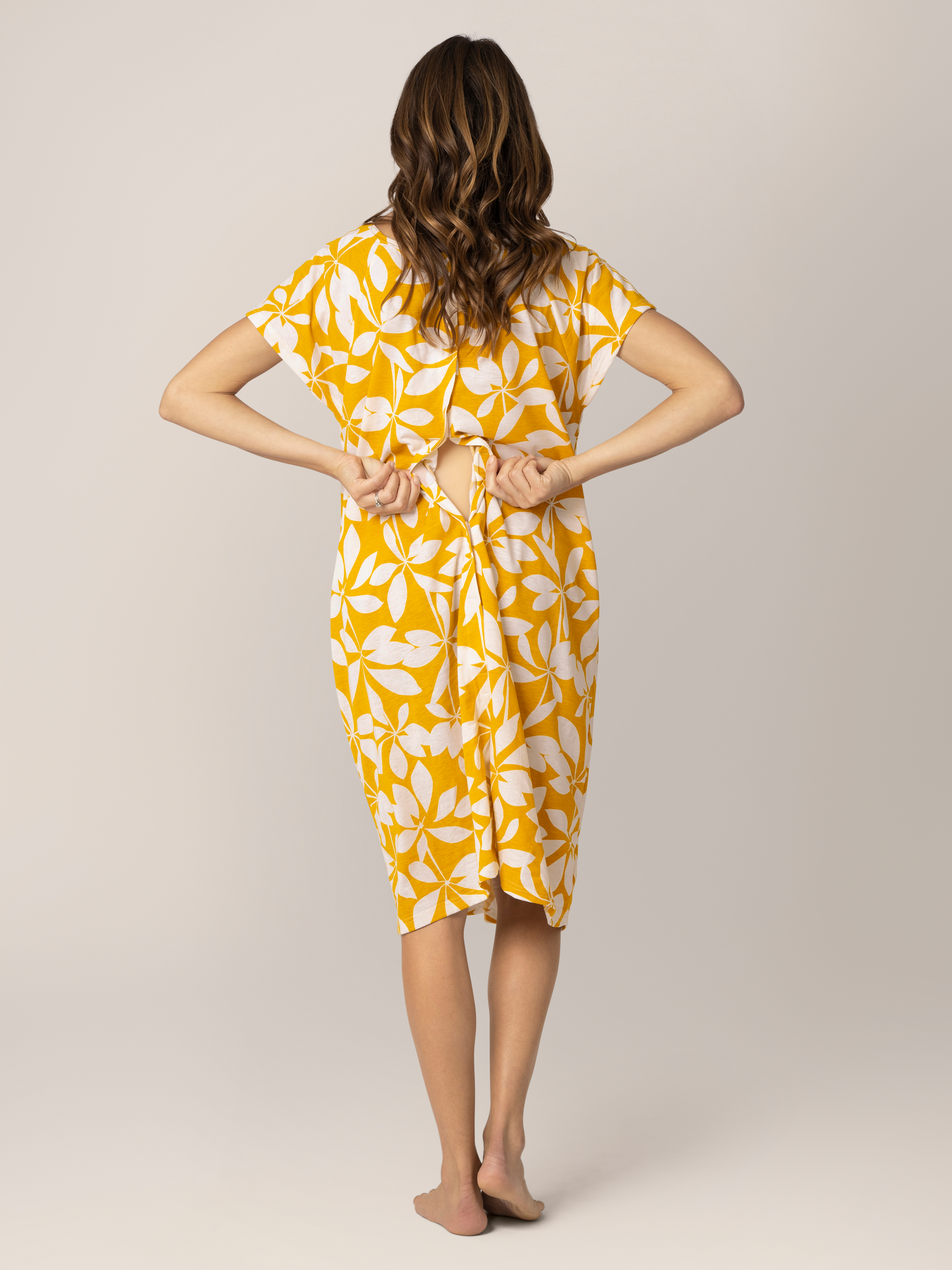 Back view of pregnant model wearing the Universal Labor & Delivery Gown in Honey Leaf, showing opening detail