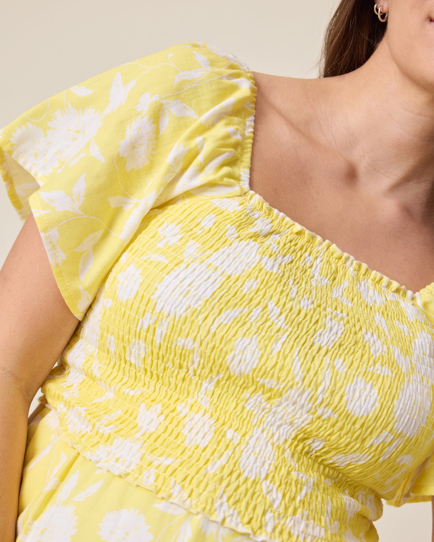 the Lola Smocked Maternity & Nursing Midi Dress in a Yellow Floral print with ruffled sleeves on a neutral background