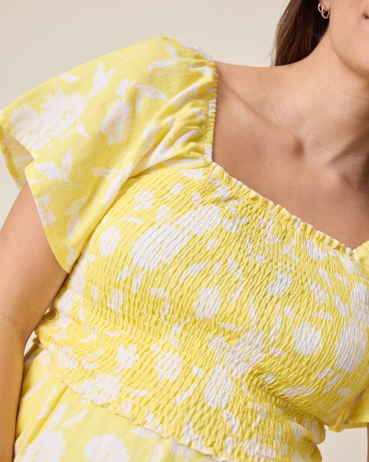 the Lola Smocked Maternity & Nursing Midi Dress in a Yellow Floral print with ruffled sleeves on a neutral background