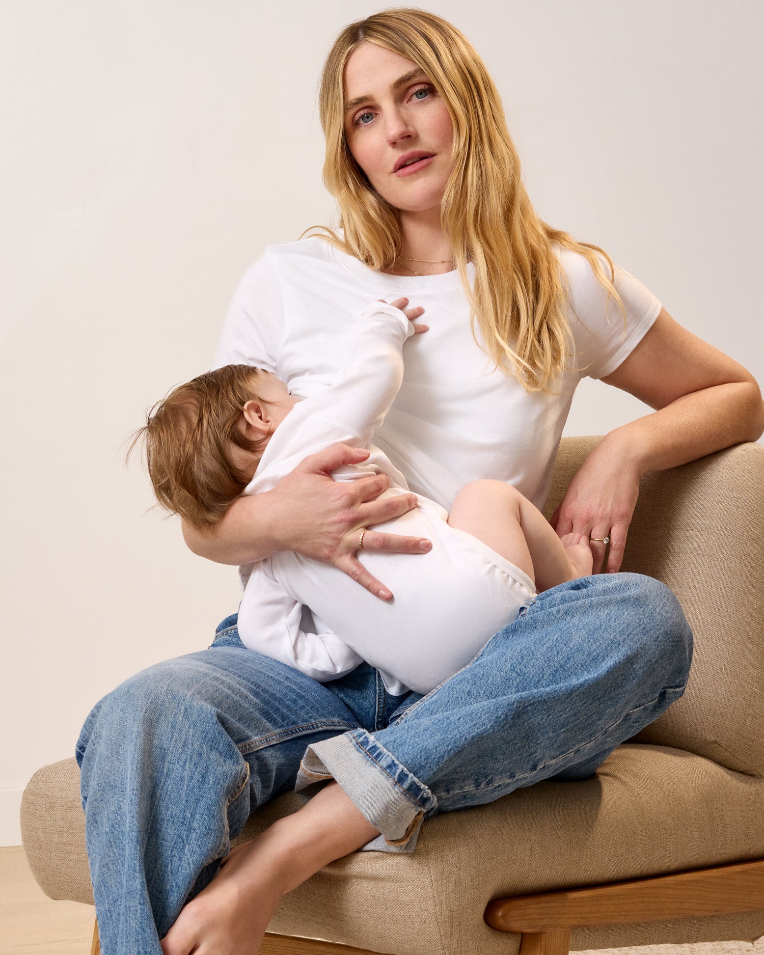 Model wearing Slim Fit Cotton Nursing T-shirt in White sitting on a lounging chair and nursing