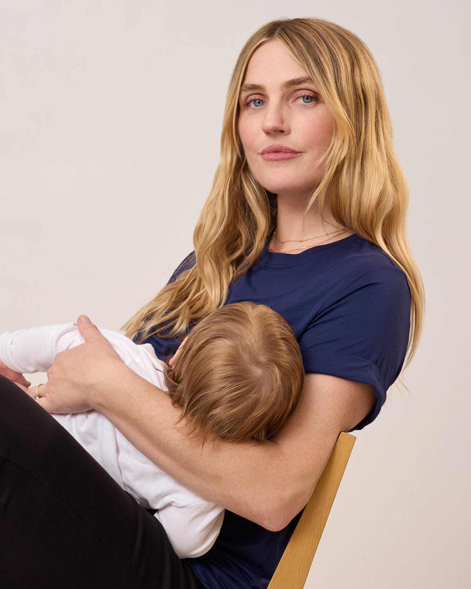 Model wearing the Asymmetrical Nursing T-shirt in Navy nursing a baby