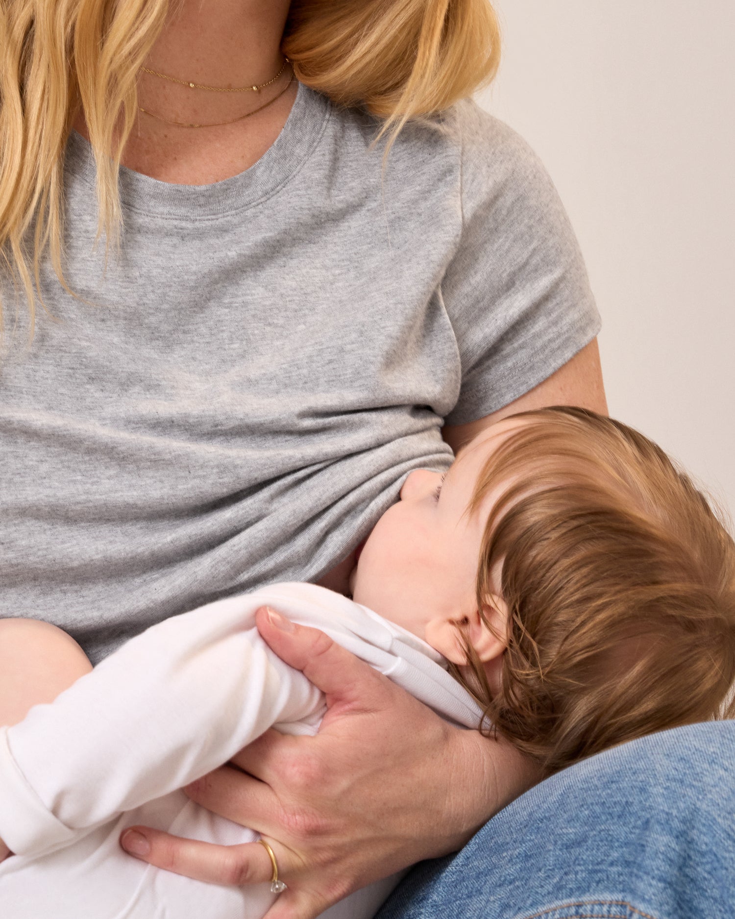 Model wearing the Slim Fit Modal Nursing T-shirt in Grey Heather nursing a baby