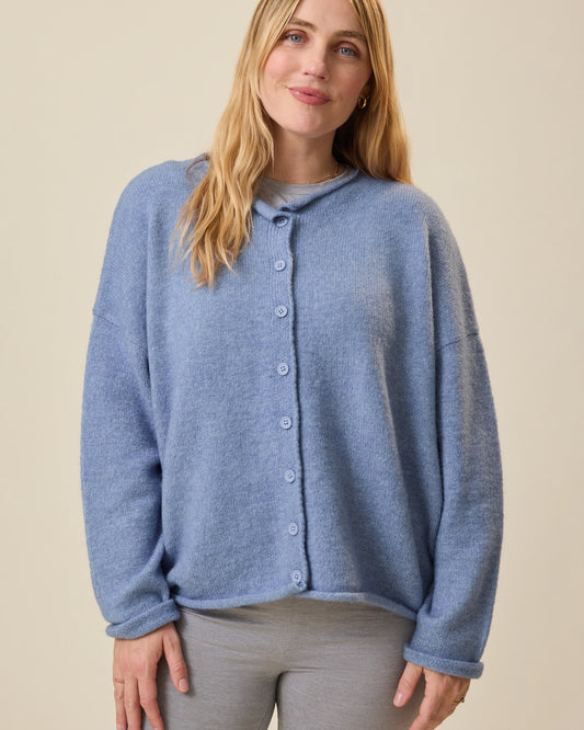 Woman wearing a blue cardigan against a beige background@model_info:Lauren is wearing a Medium.