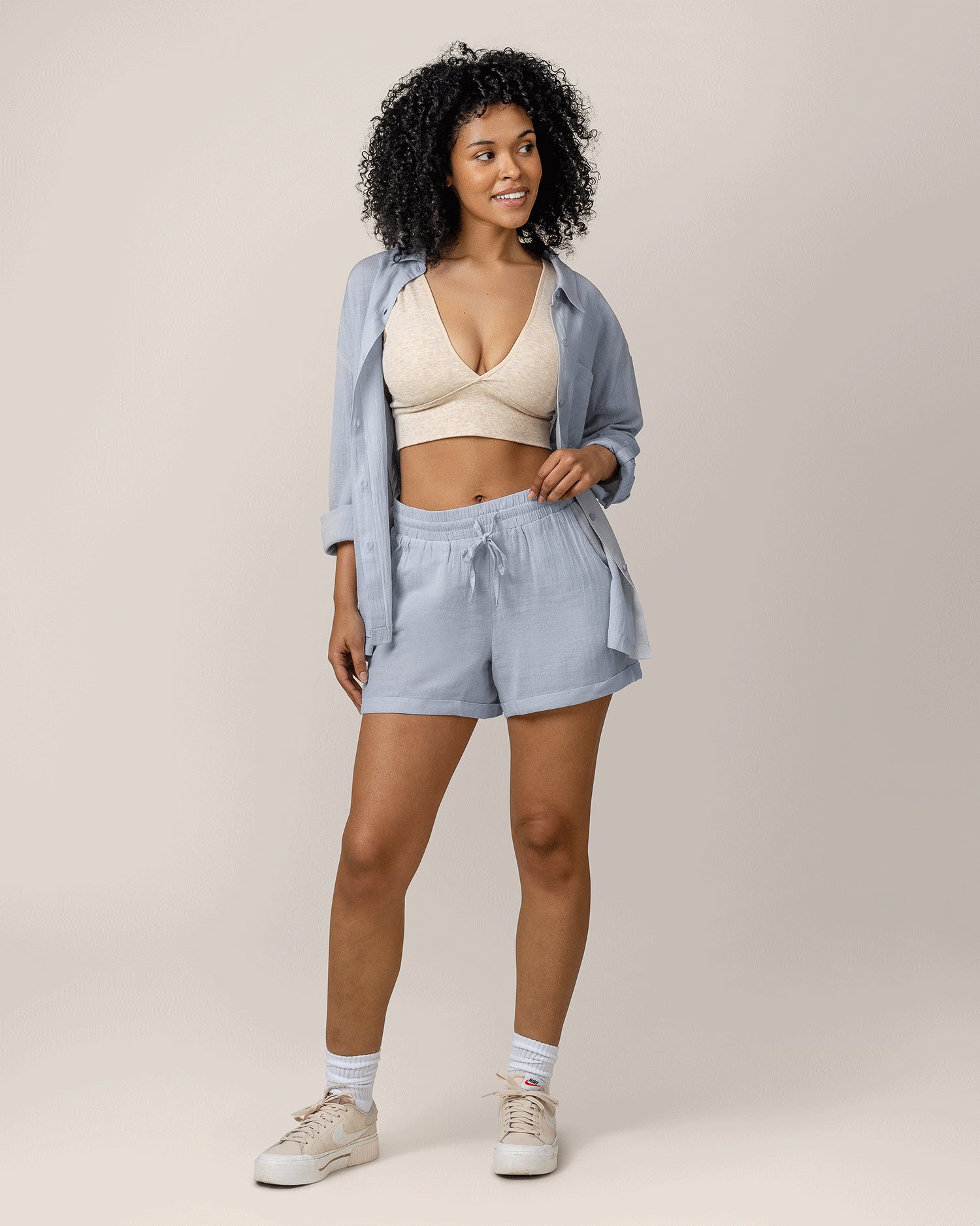 Model wearing the Reese Oversized Linen Button Down Shirt in French Blue, unbuttoned with Sublime® Bamboo Maternity & Nursing Plunge Bra in Oatmeal Heather under, paired with matching Reese Linen Short, and styled with tennis shoes