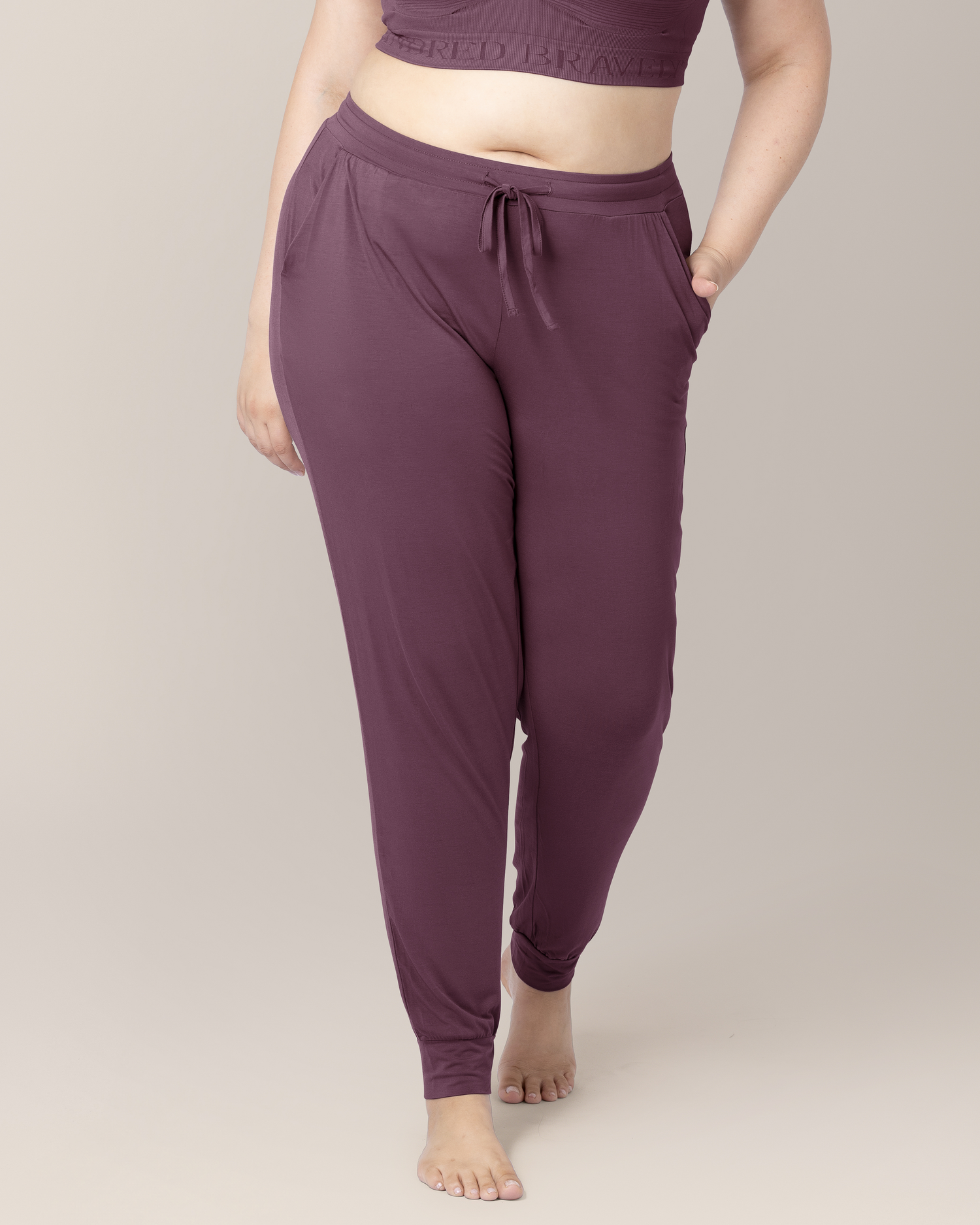 Cropped in front view of model wearing the Everyday Lounge Jogger in Burgundy Plum, with one hand in pocket, highlighting waistband and drawstring
