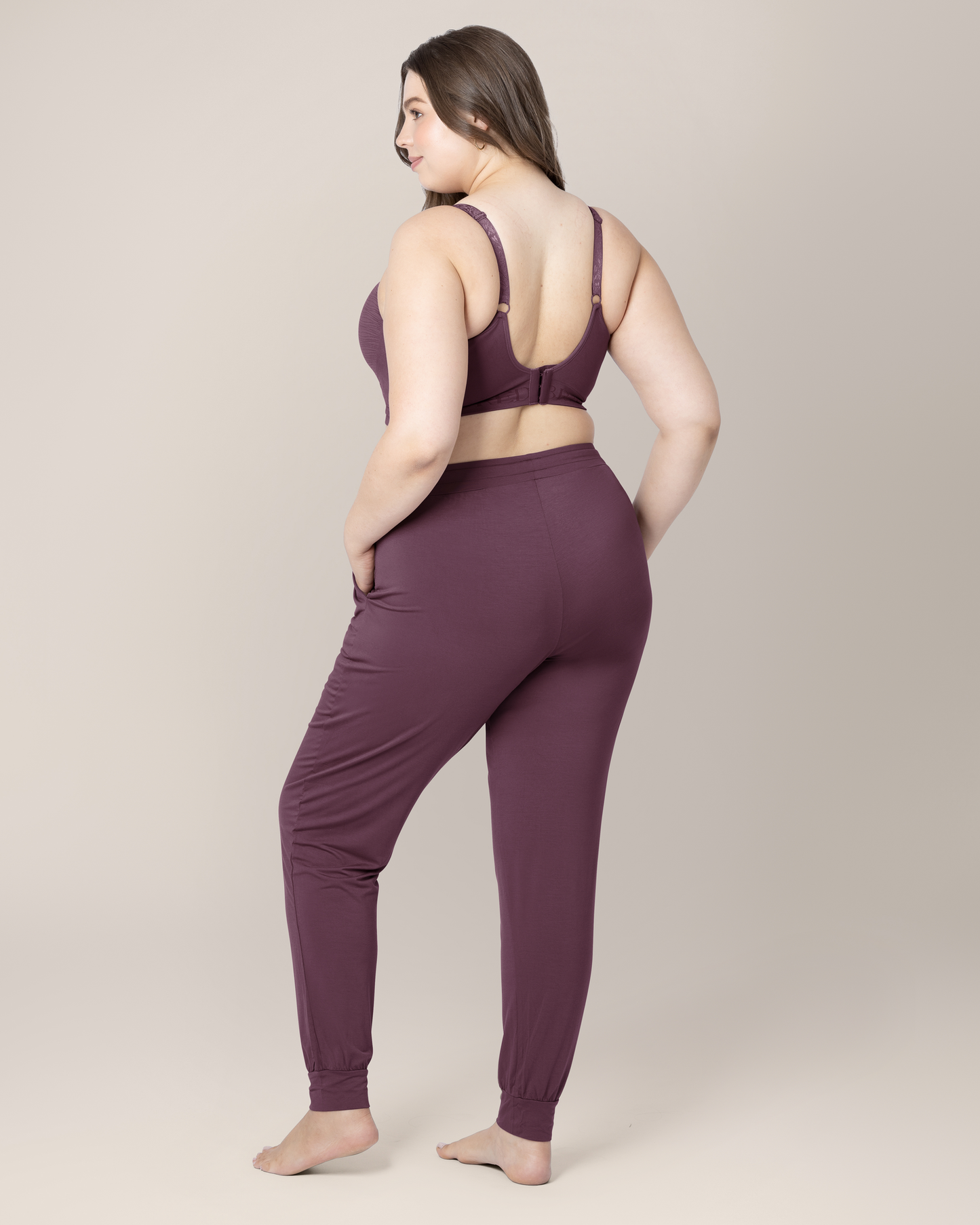 3/4 back view of model wearing the Everyday Lounge Jogger in Burgundy Plum, paired with matching Sublime® Hands-Free Pumping & Nursing Bra