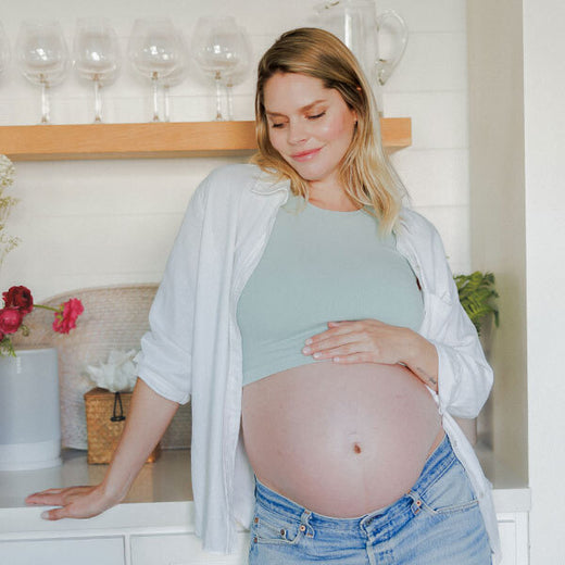 Model leaning on the counter while wearing the Sublime® Bamboo Maternity & Nursing Longline Bra Top in Aqua Mist