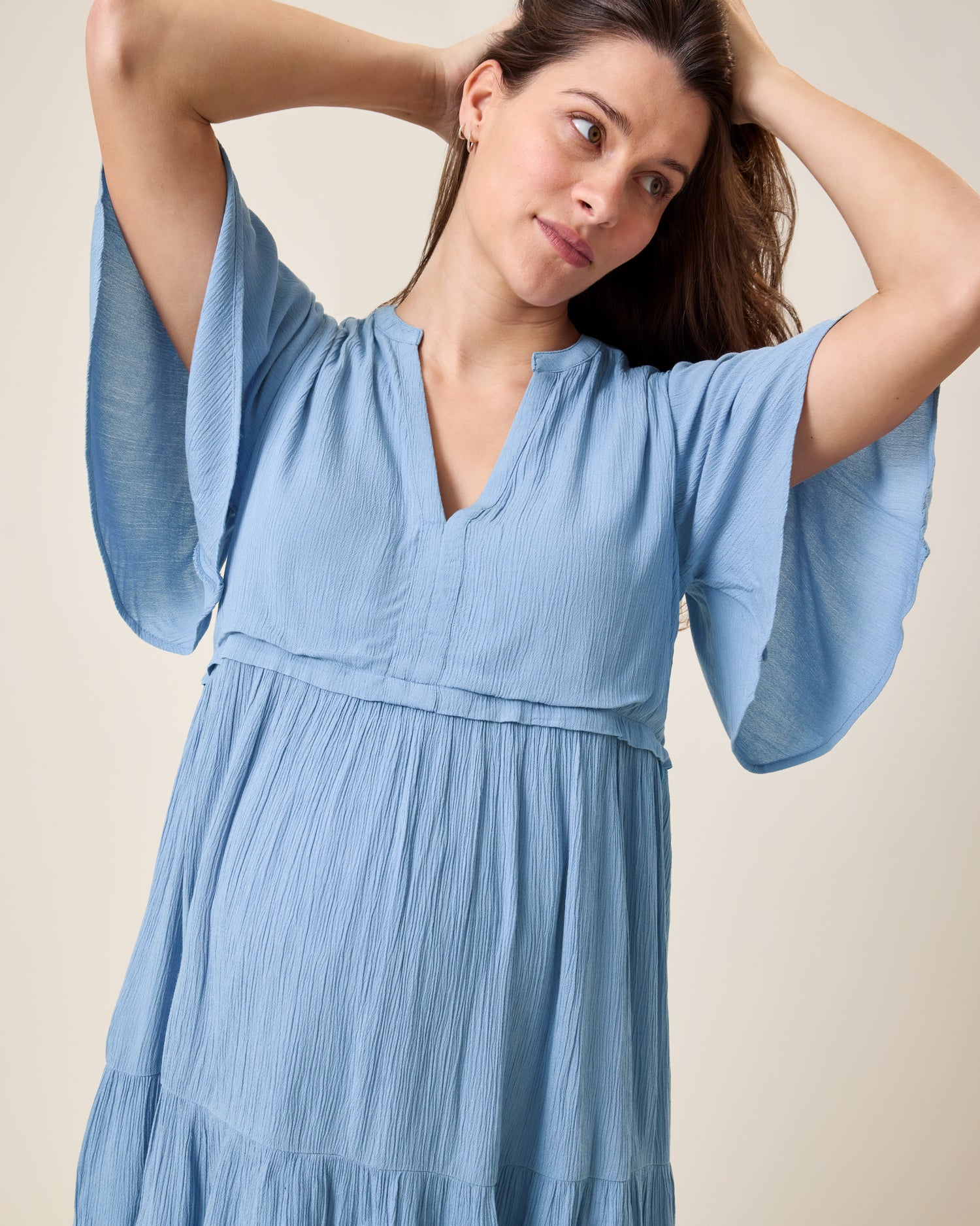 Front view of model wearing Marlowe Maternity & Nursing Mini Dress in Vintage Blue on a neutral background and showing the flared short sleeves design
