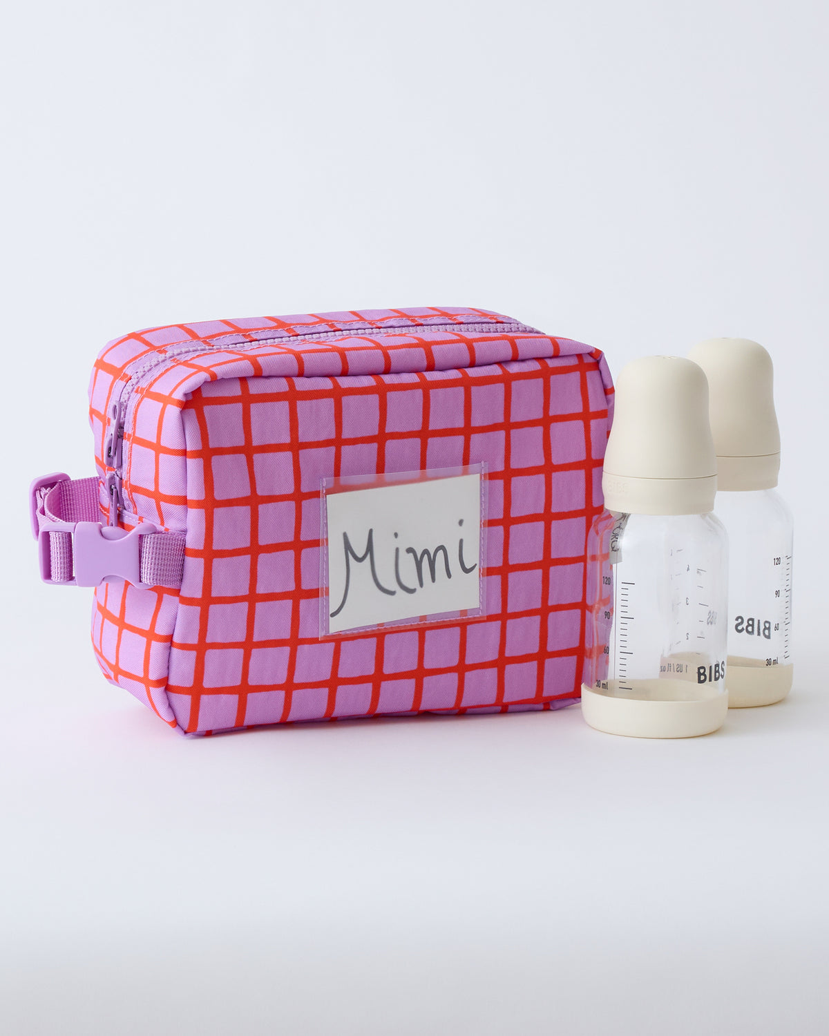 Mini Cooler Bag in Orchid Grid, with name tag inside clear slip pocket, and two milk bottles, on a beige background.