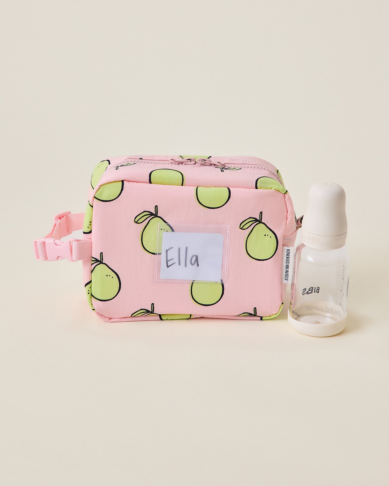 Pink Mini Cooler Bag with green pomelo pattern on a beige background sitting next to a bottle