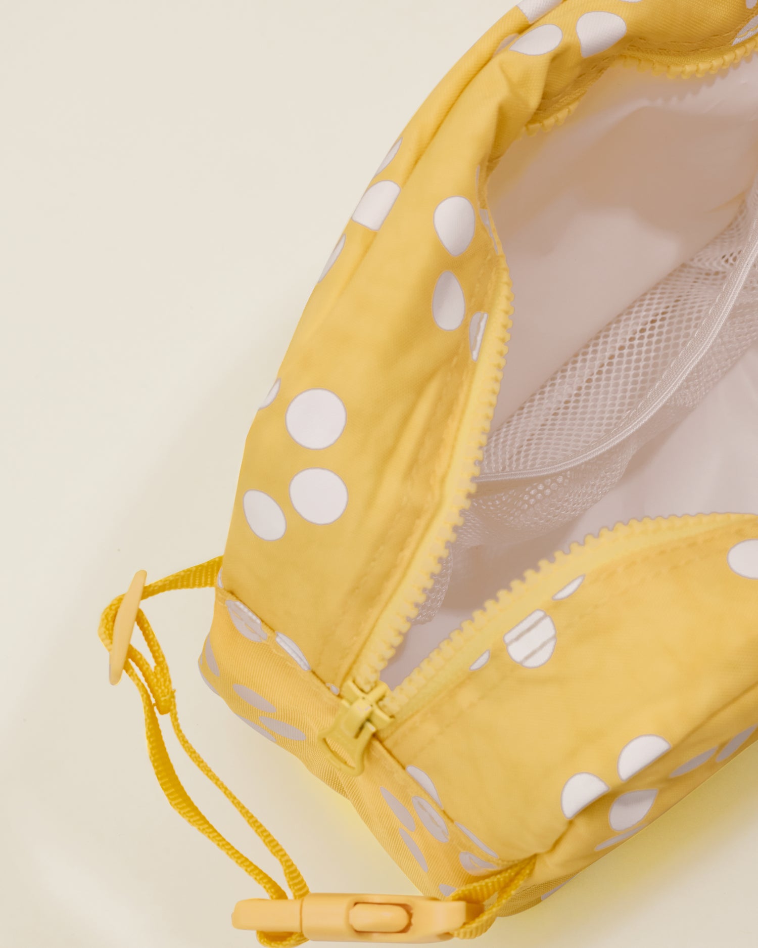 Close up of the Mini Cooler Bag in the Sunshine Dots print, unzipped showing pocket inside and detail of a handle with a clasp