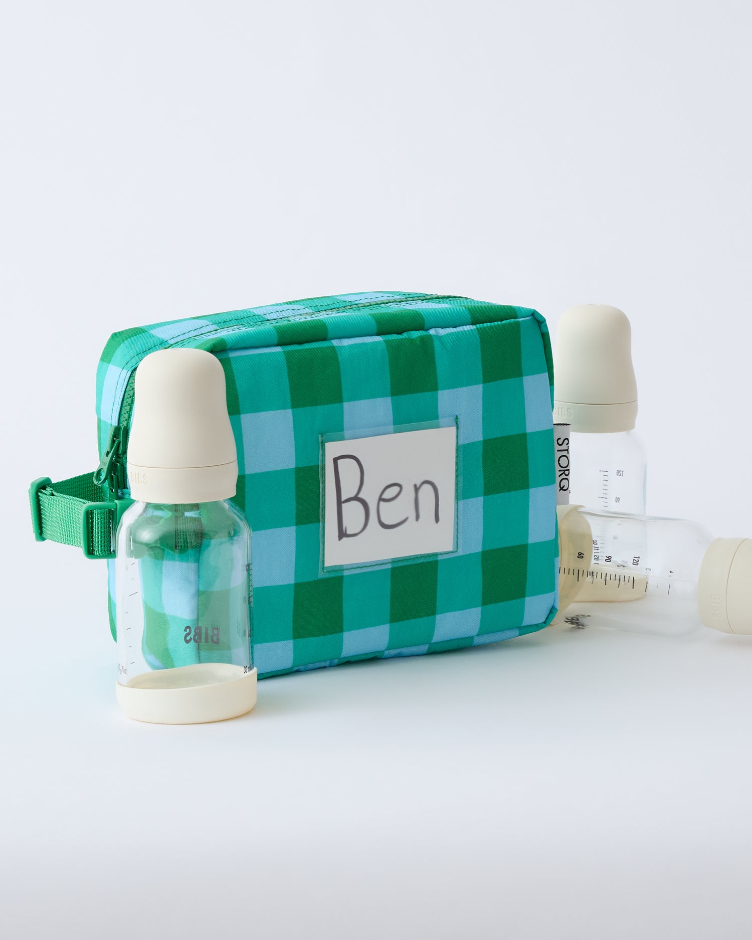 Mini Cooler Bag in Teal Gingham, with name tag in clear slip pocket, and three milk bottles, on a beige background.