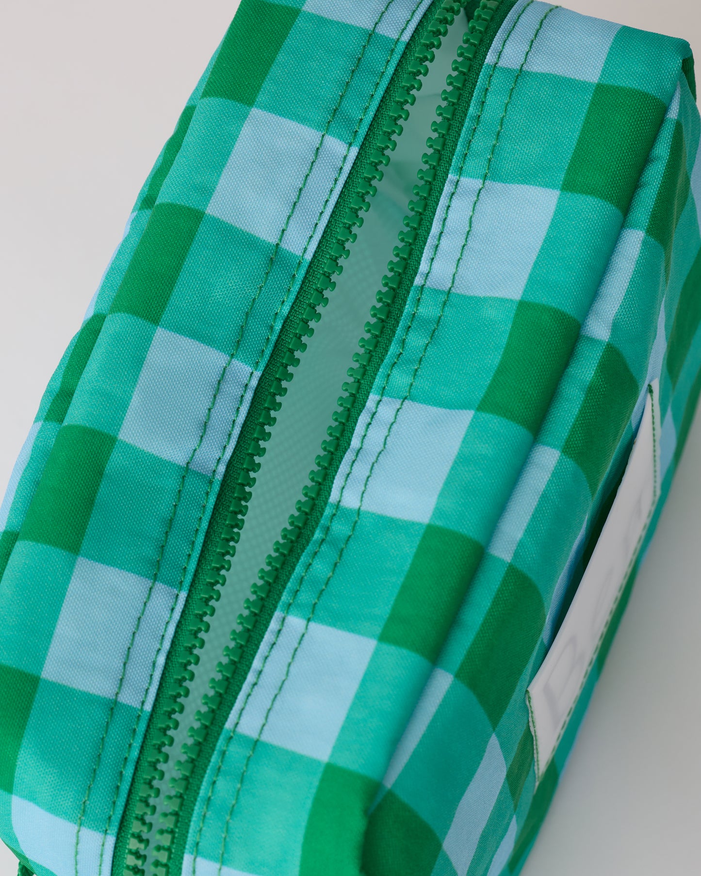 Close up of zipper and interior of the Mini Cooler Bag in Teal Gingham, on a beige background.
