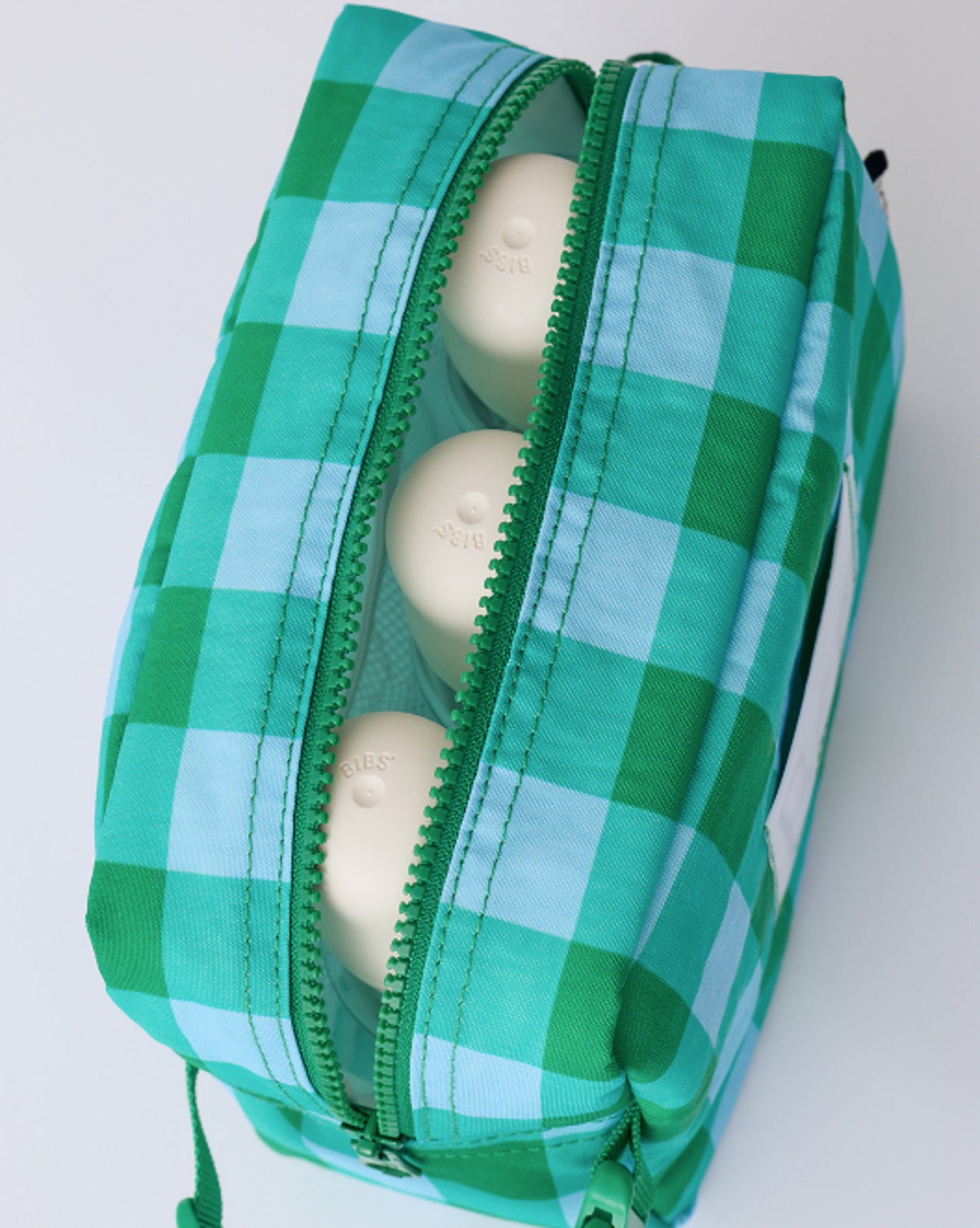 Close up of zipper and interior of Mini Cooler Bag in Teal Gingham, with three milk bottles inside, on a beige background.