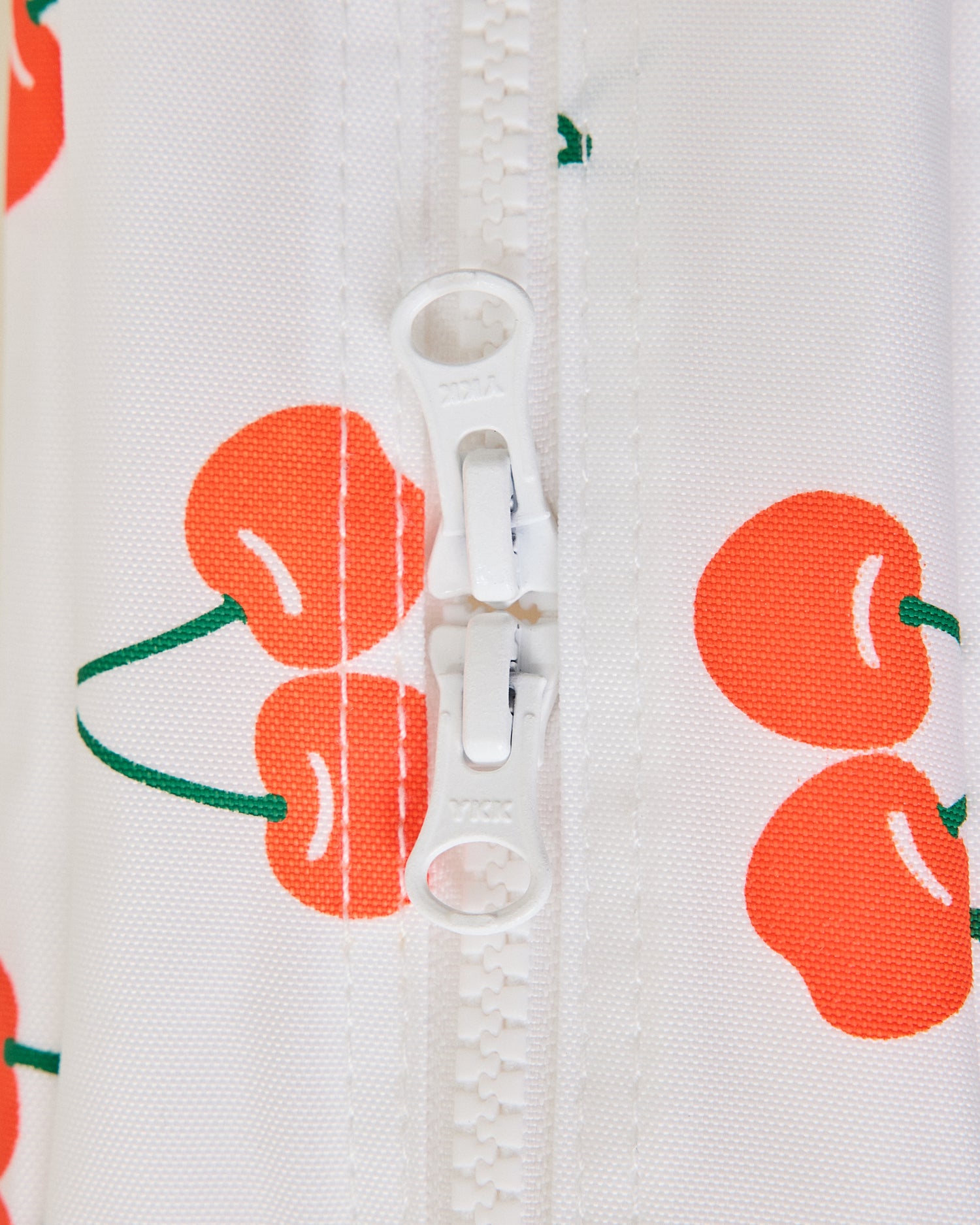 Close-up of a zipper on the Mini Cooler Bag with red cherry pattern on white background