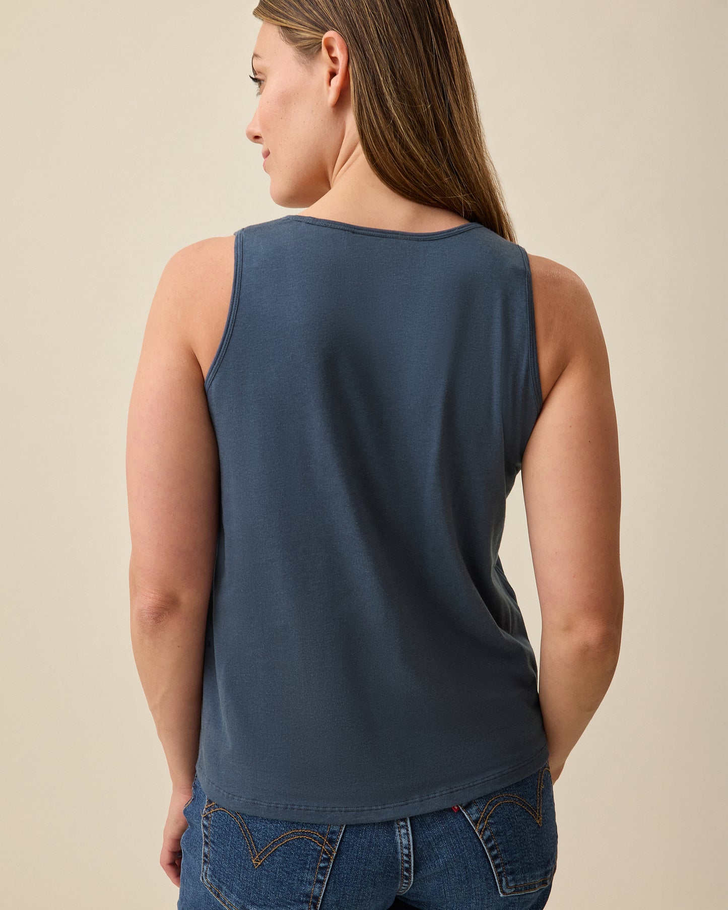Model is showing back view of Modal Signature Nursing Tank in Midnight Blue on a beige background.