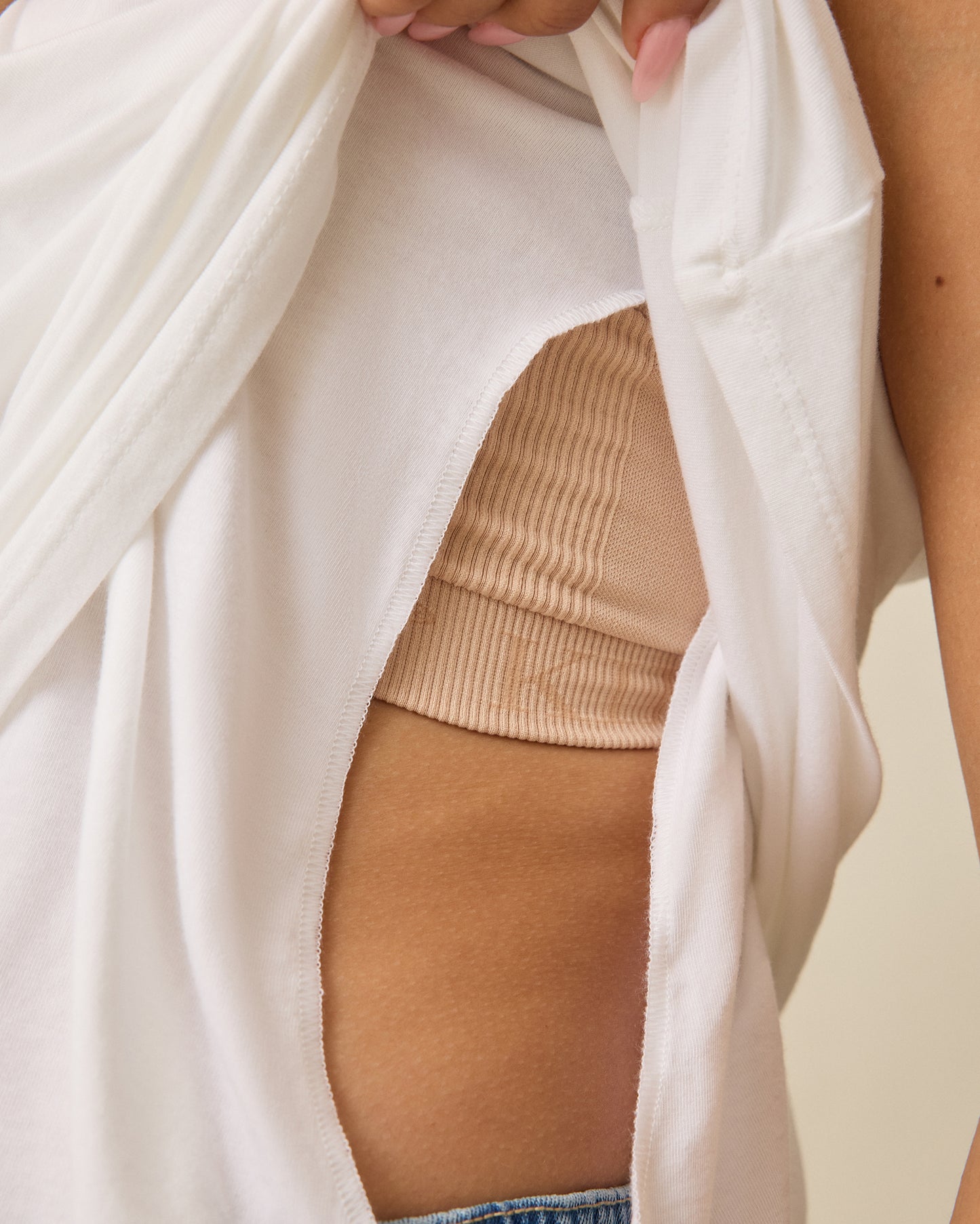 Model is showing easy side breastfeeding access of Modal Signature Nursing Tank in White on a beige background.