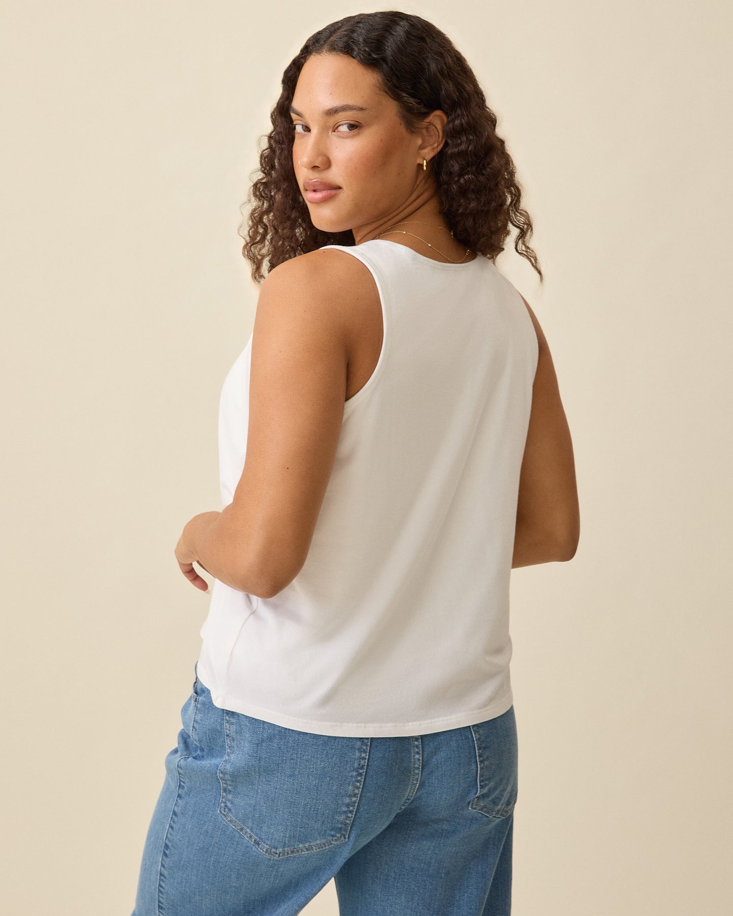 Model is showing back view of Modal Signature Nursing Tank in White on a beige background.