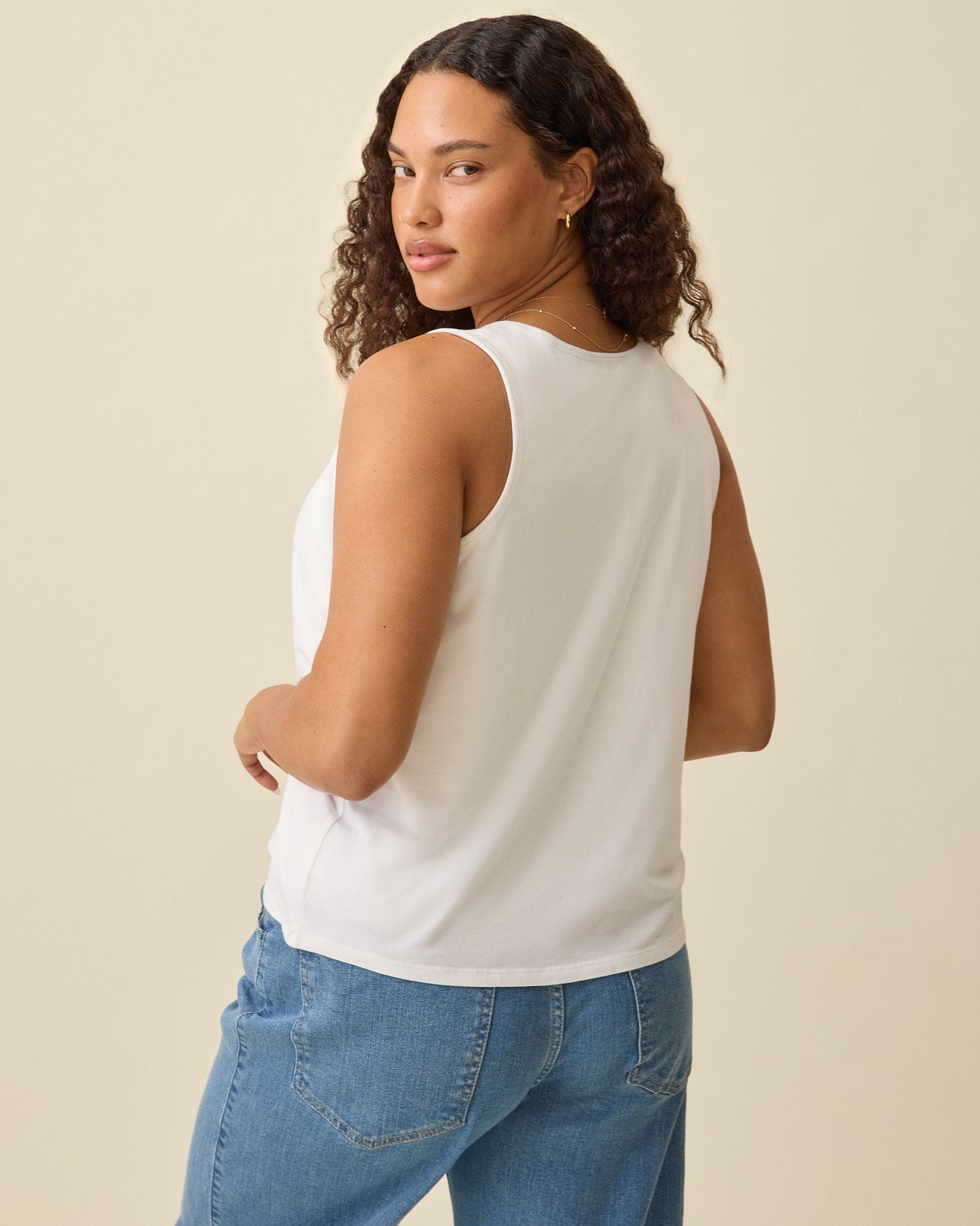 Model is showing back view of Modal Signature Nursing Tank in White on a beige background.