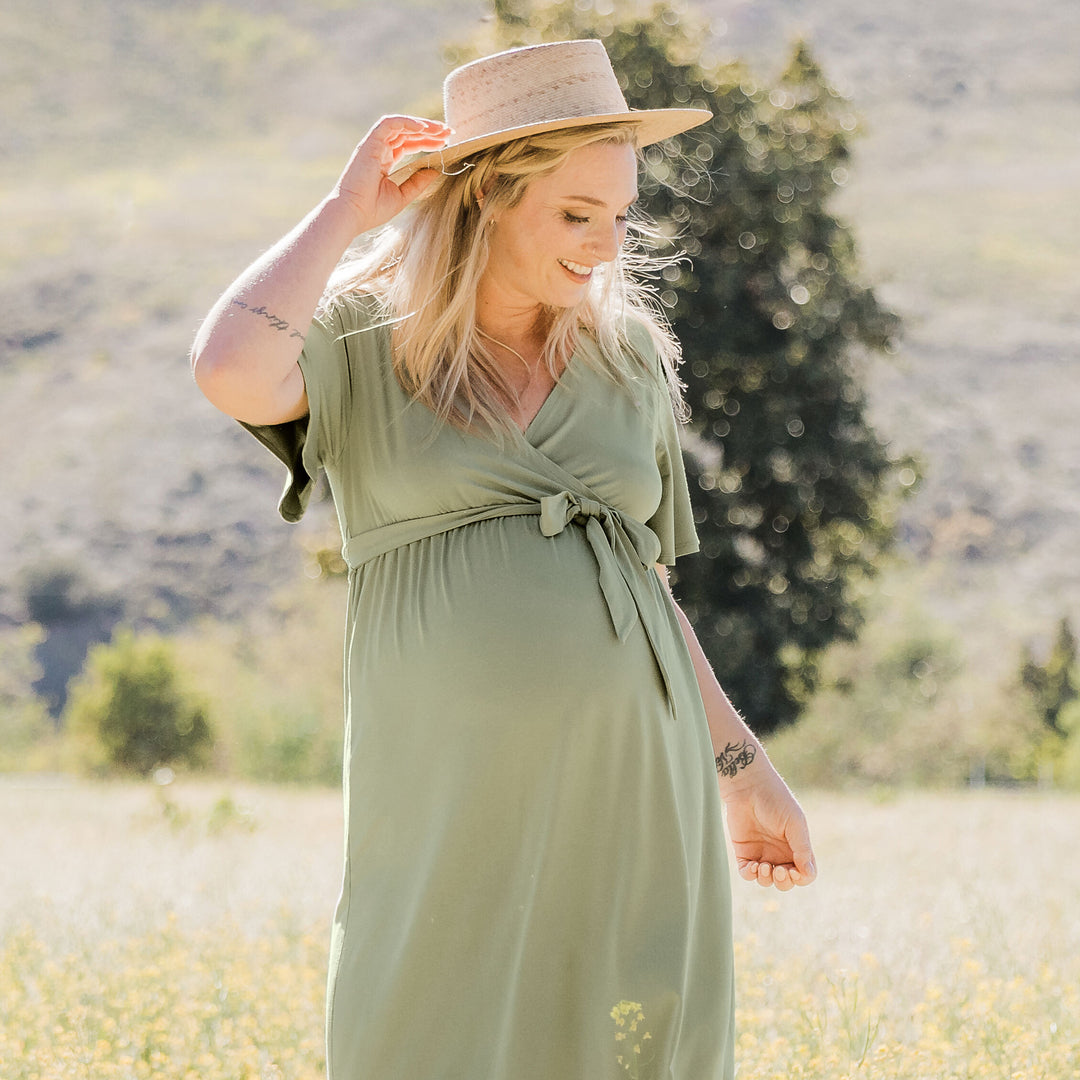 Model standing outside in a hat wearing the Wrap Maternity Maxi Dress in Rosemary.