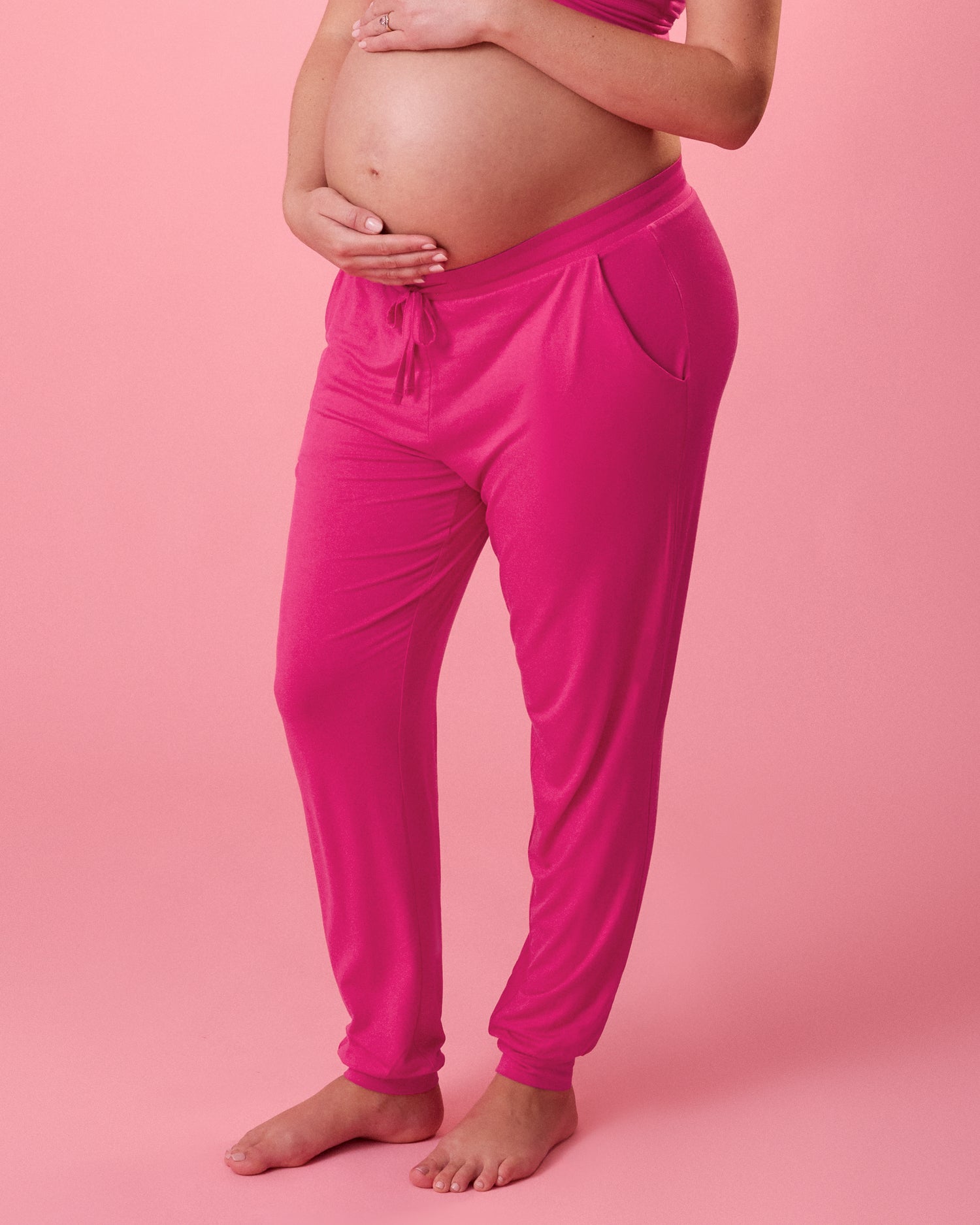 Front view of model wearing Ultralight Sleep & Lounge Jogger in Raspberry Pink on a pink background@model_info:Megan is 5'9" and wearing a Medium Long.