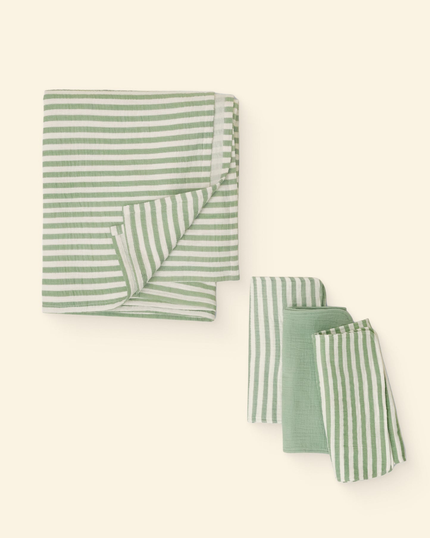 Set of green and white striped burp cloths and swaddle on a light background