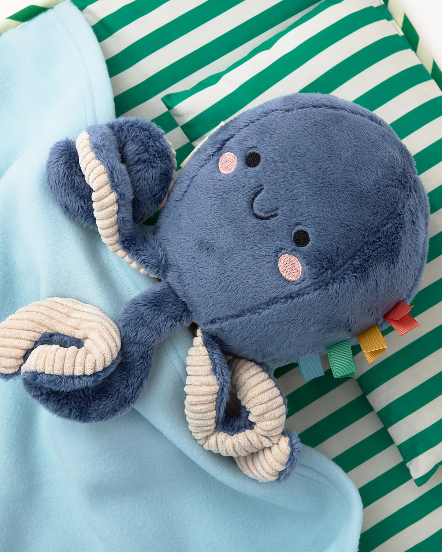 Cute octopus doll laying on the pillow of the Nap Mat in Green Stripe with lightly padded mat, pillow and light blue Soft fleece blanket that can fold over, velcro closure, handle for carrying, on a white background.