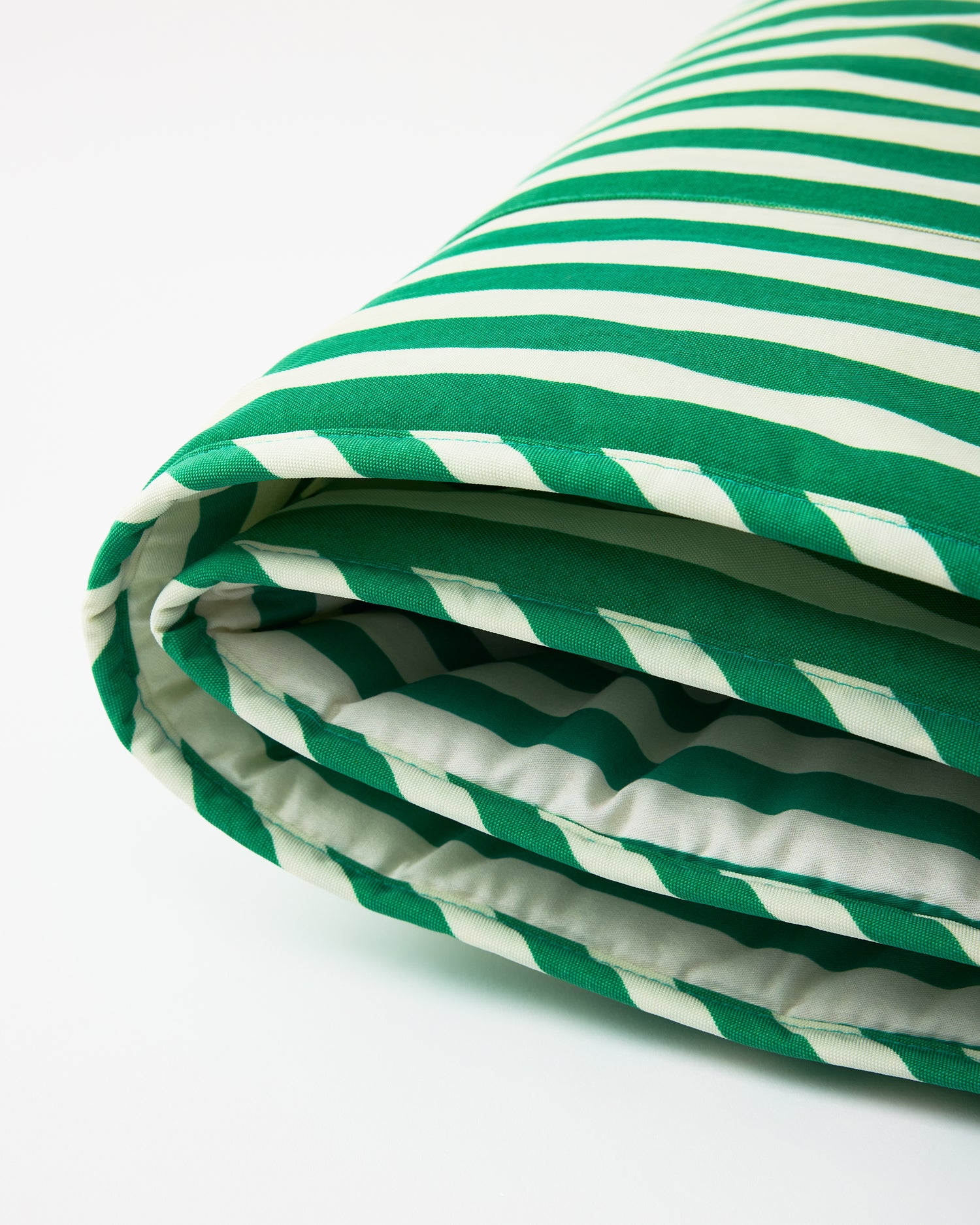 Close up of the Nap Mat in Green Stripe, easily folded to display light padding for comfort, on a white background.