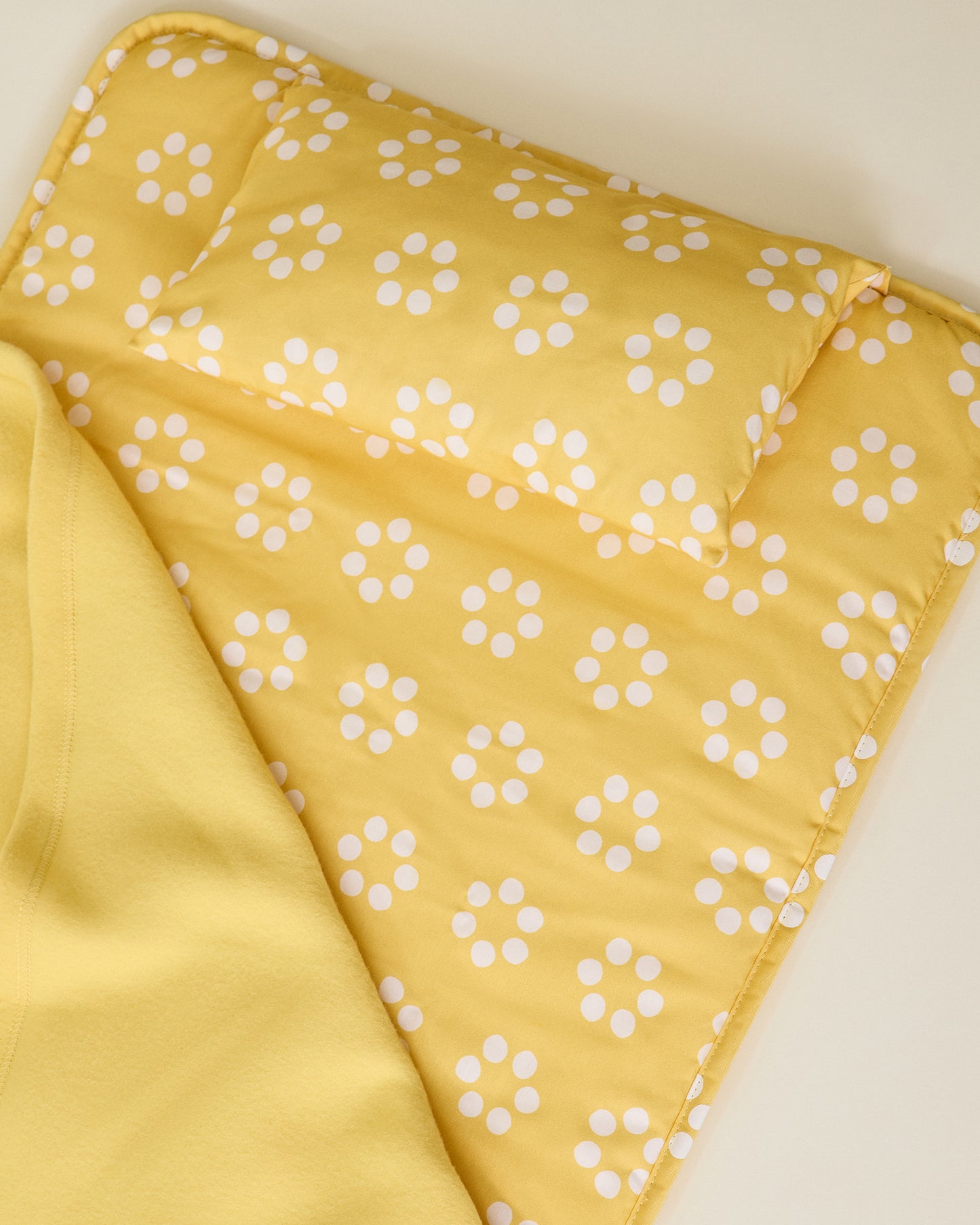 Nap Mat in yellow sunshine dots pattern showing matching pillow on beige background