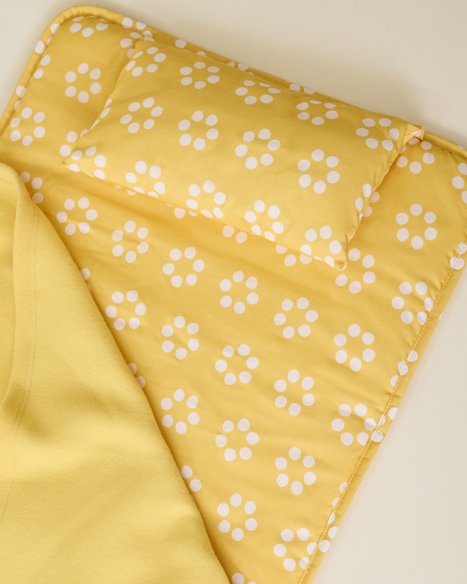 Nap Mat in yellow sunshine dots pattern showing matching pillow on beige background