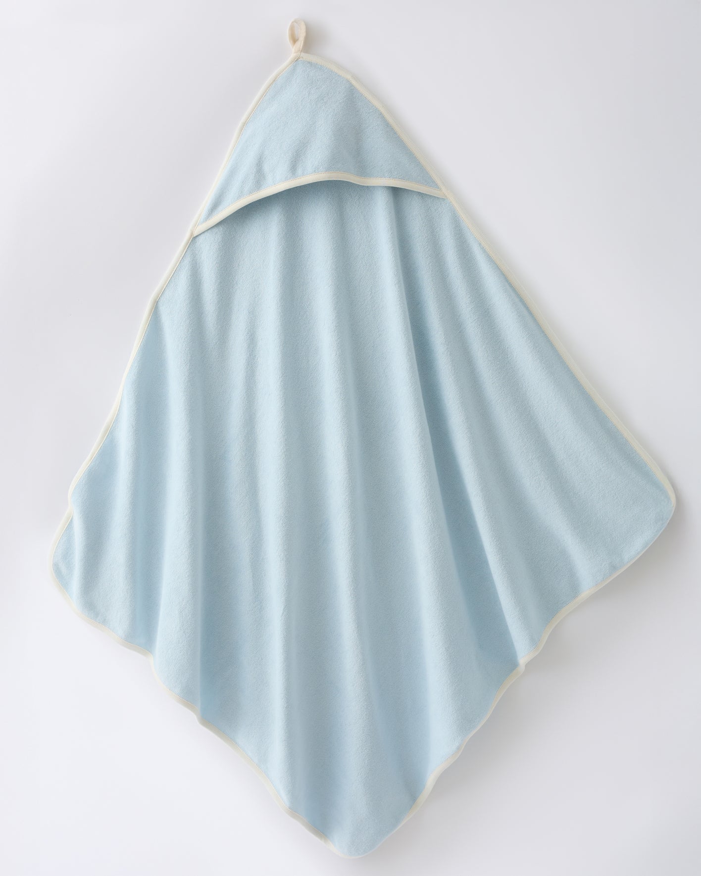 Hooded towel in the Newborn Bath Set in Breeze, on a beige background.